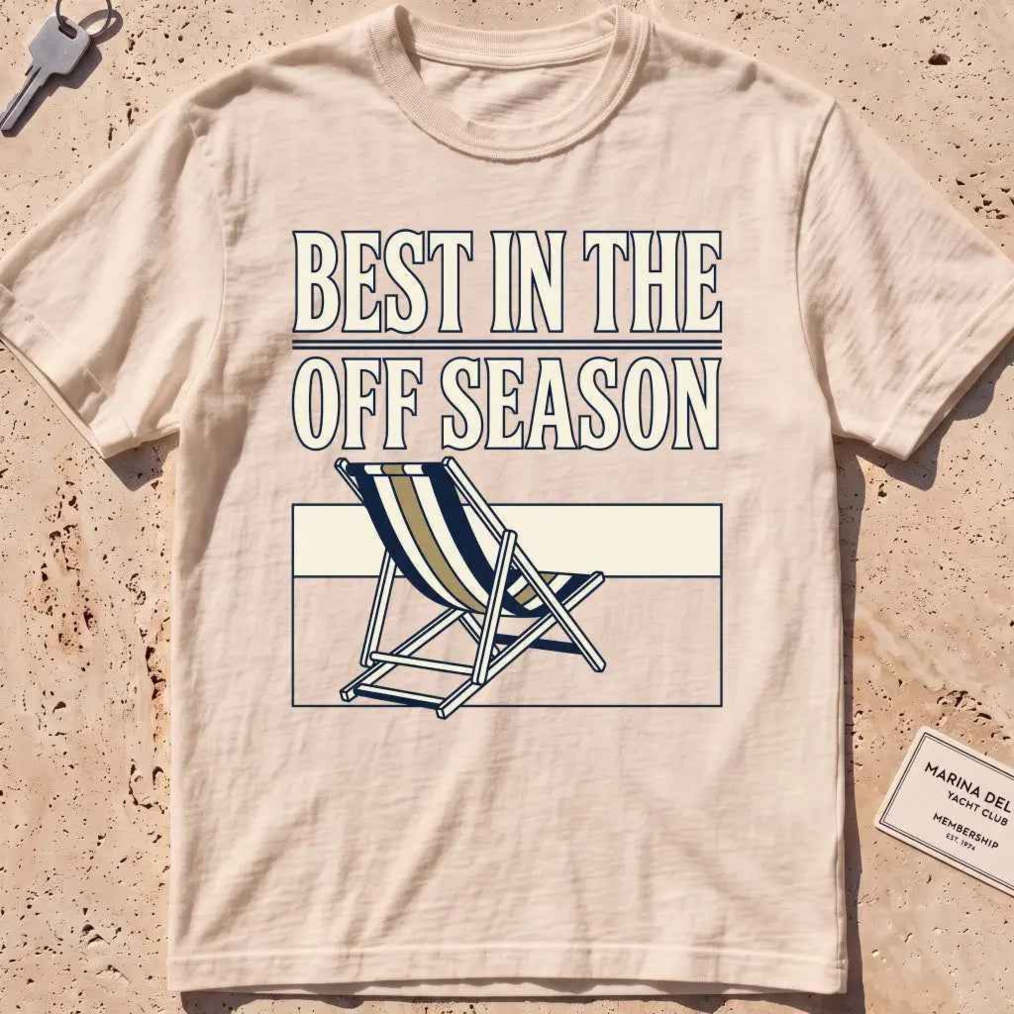 Ivory heavyweight tee with "Best in the Off Season" text and an empty deckchair graphic.