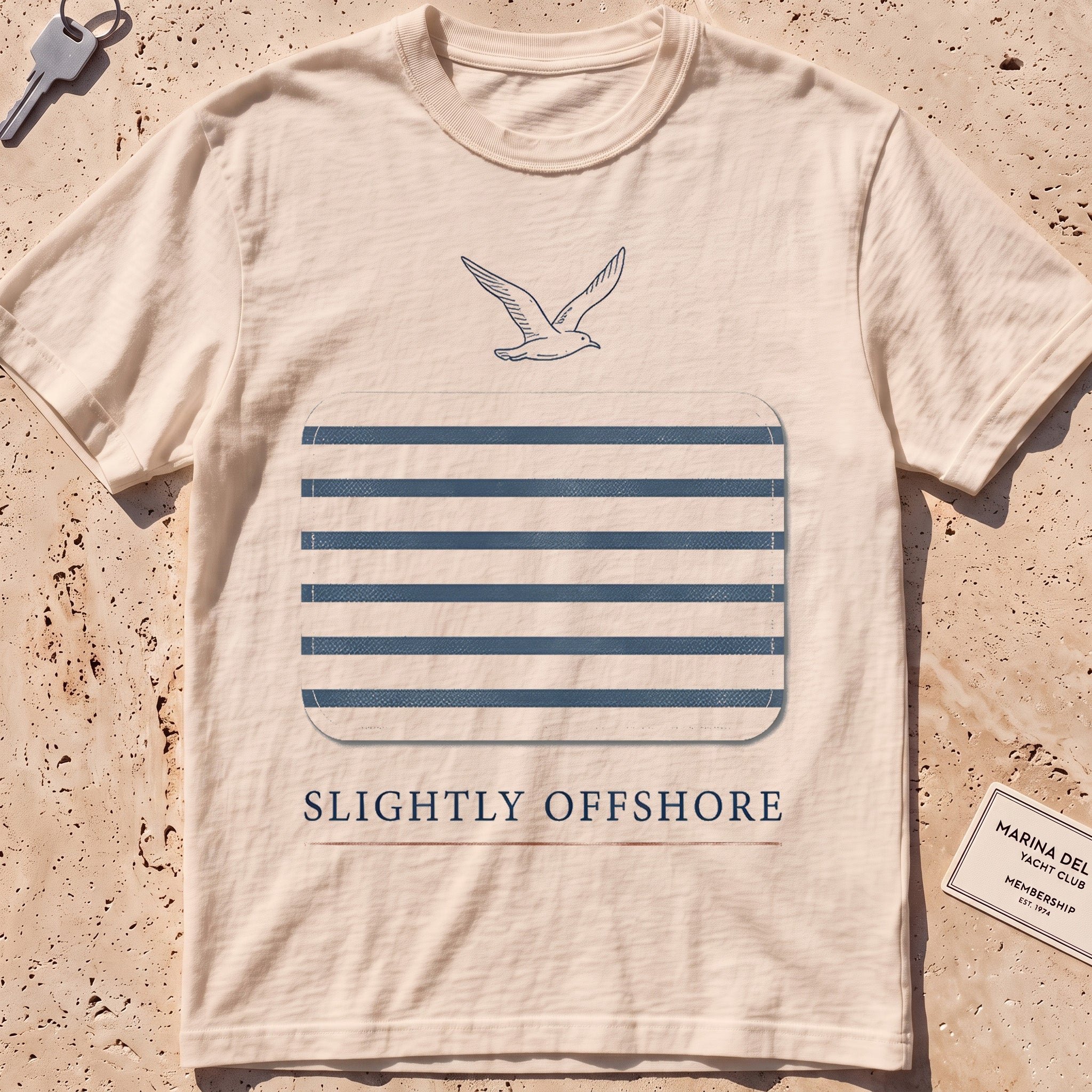 ivory heavyweight tee with a Breton-stripe patch and a small seabird graphic.