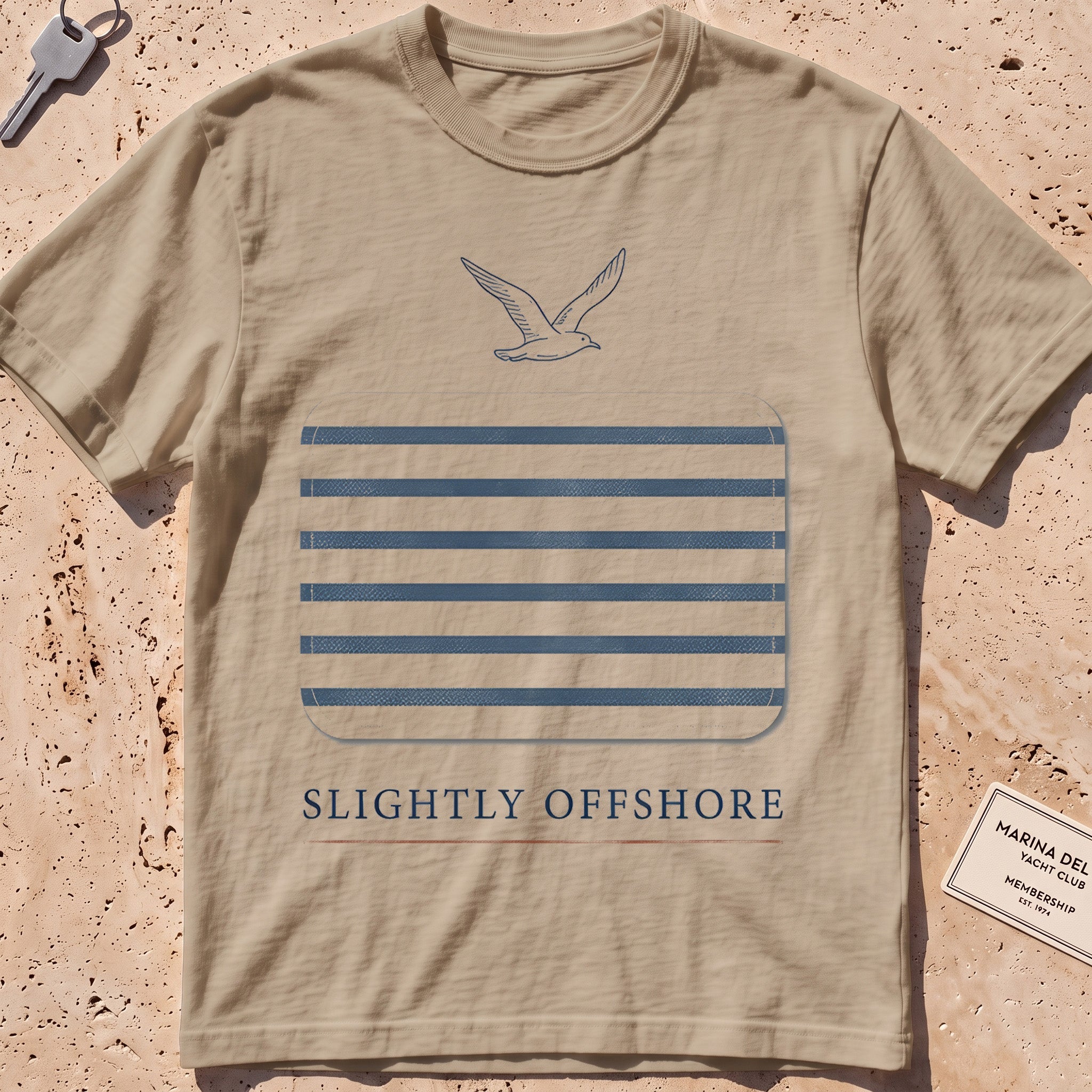 khaki heavyweight tee with a Breton-stripe patch and a small seabird graphic.