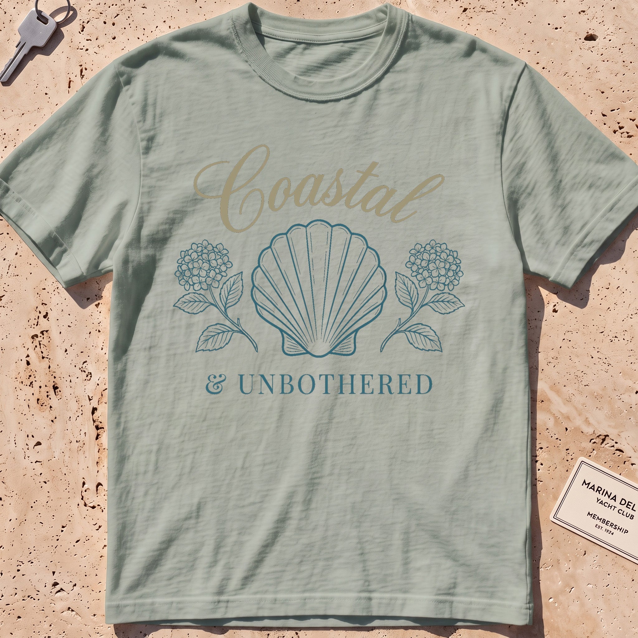 bay heavyweight tee with a shell and hydrangea "Coastal and Unbothered" graphic.