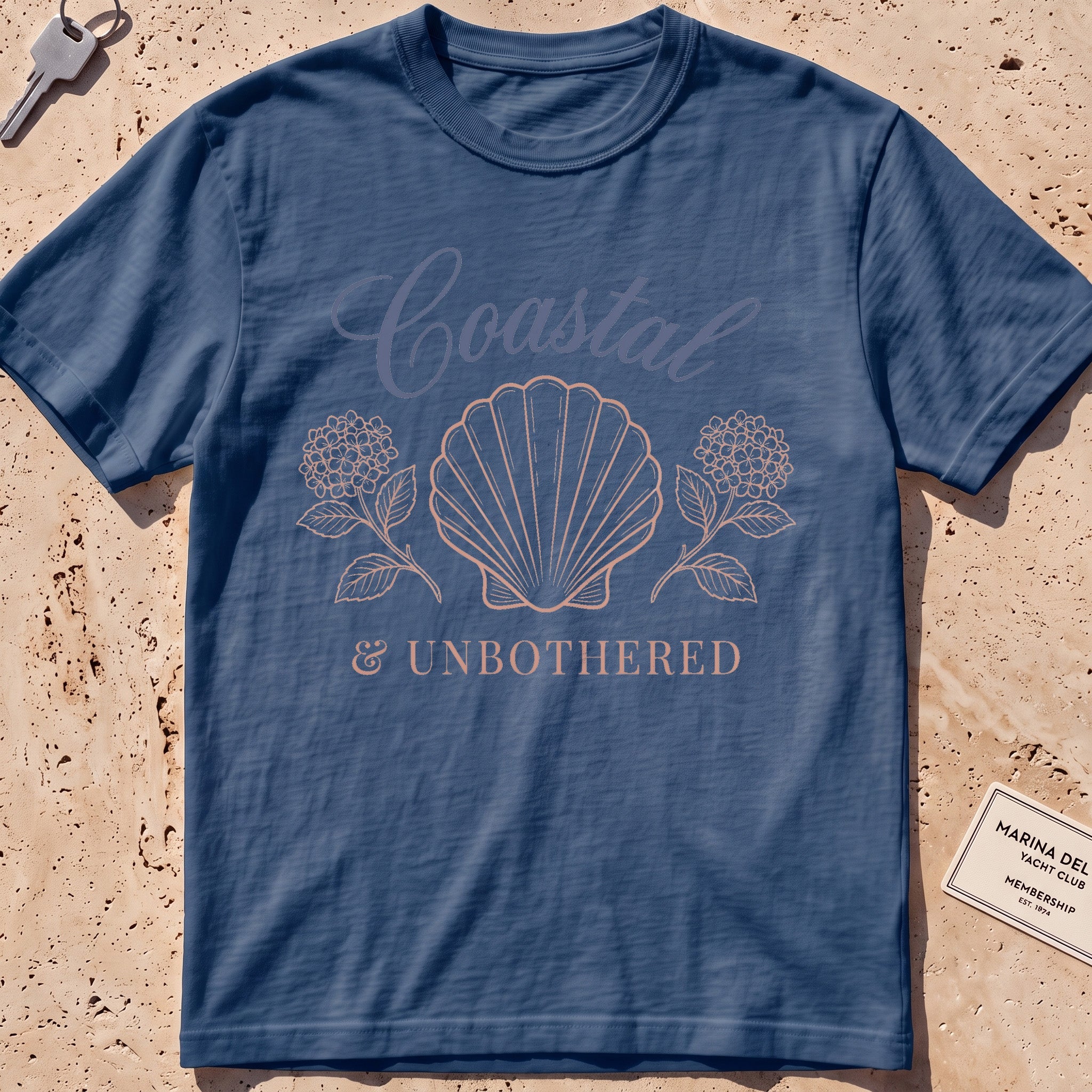 midnight heavyweight tee with a shell and hydrangea "Coastal and Unbothered" graphic.