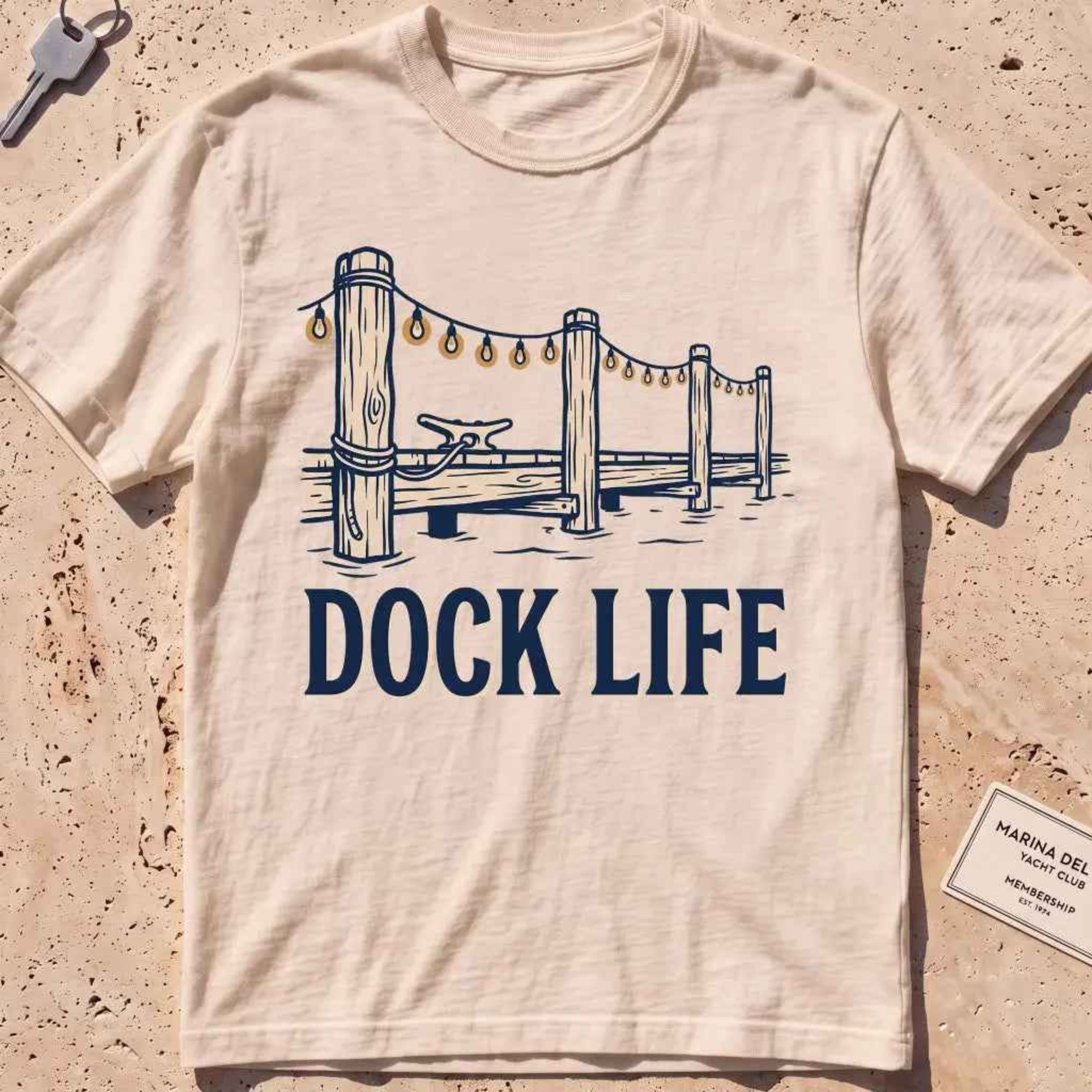 ivory heavyweight tee with dock pilings and string lights "Dock Life" graphic.