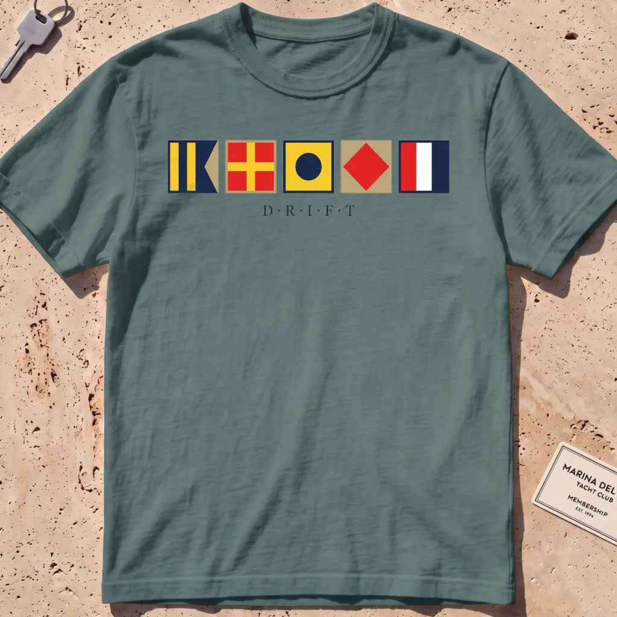 blue spruce heavyweight tee with maritime signal flags spelling out the word "DRIFT."