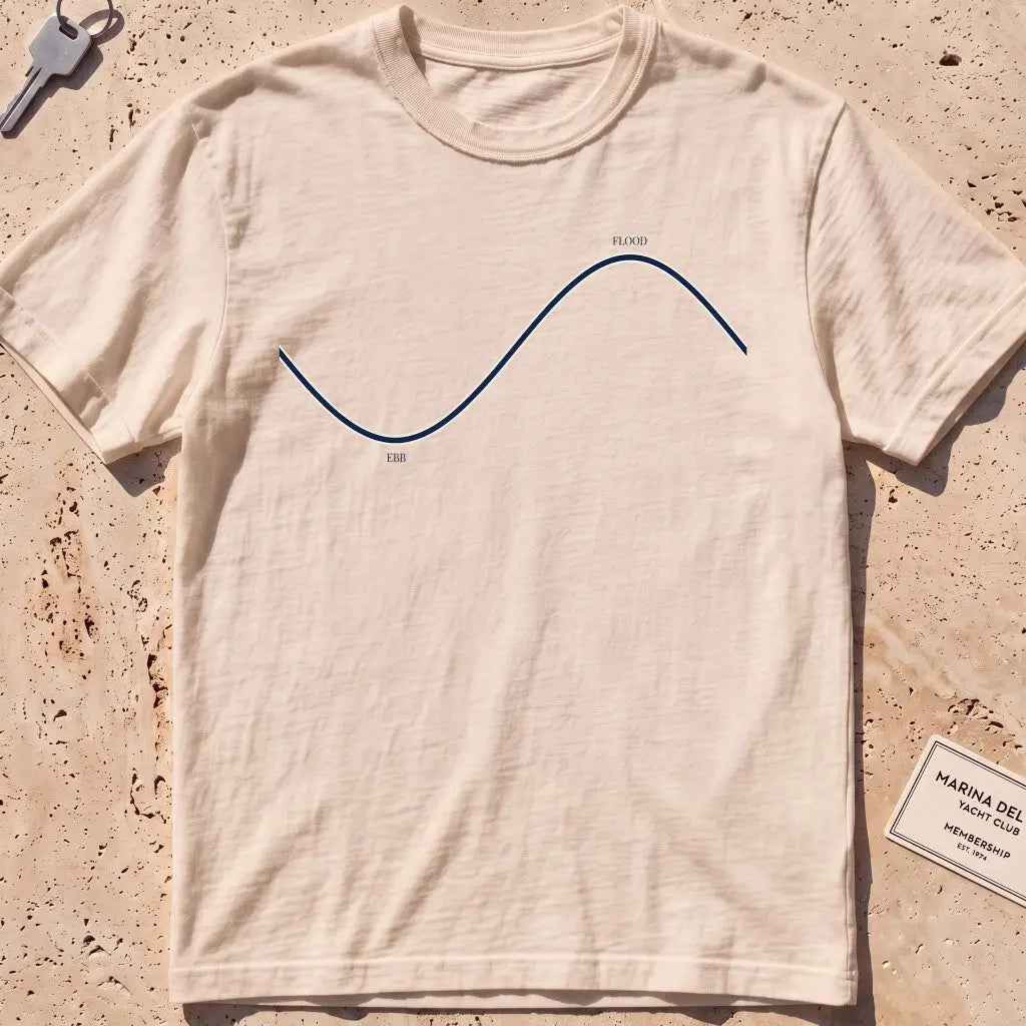 ivory heavyweight tee with a minimalist "Ebb and Flood" tide curve graphic.