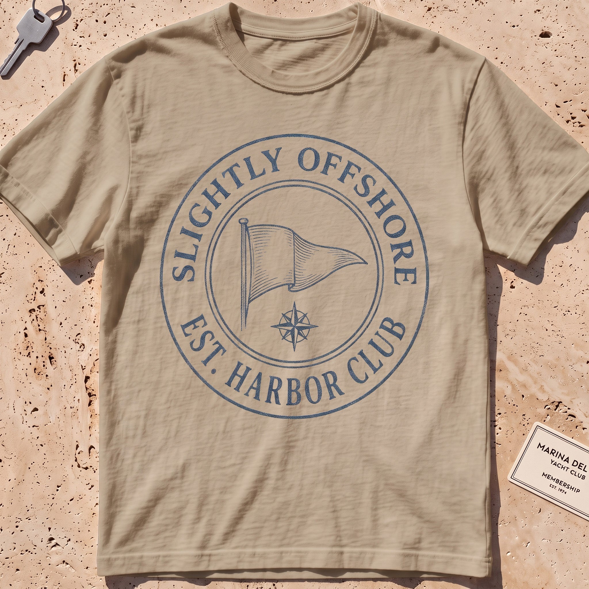 khaki heavyweight tee with an engraved burgee and compass-seal crest.