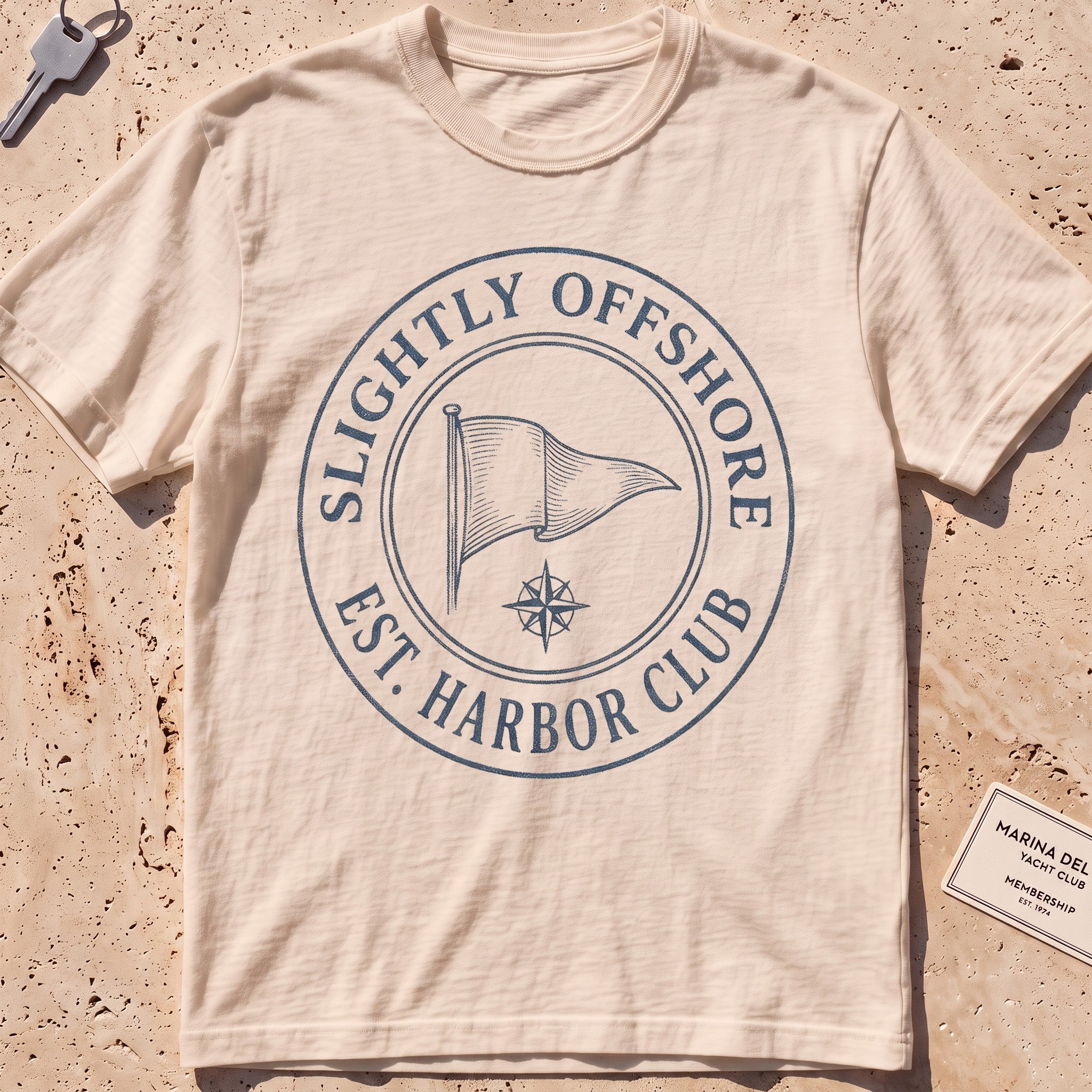 ivory heavyweight tee with an engraved burgee and compass-seal crest.