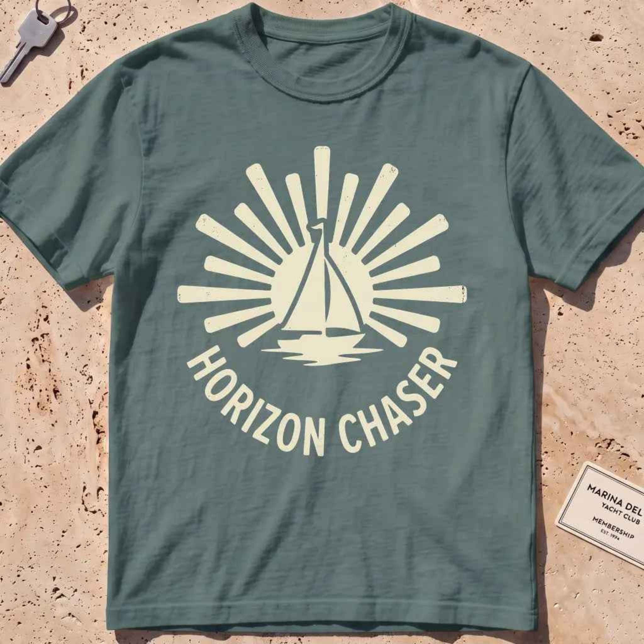 blue spruce heavyweight tee with a sunburst sailboat "Horizon Chaser" badge.