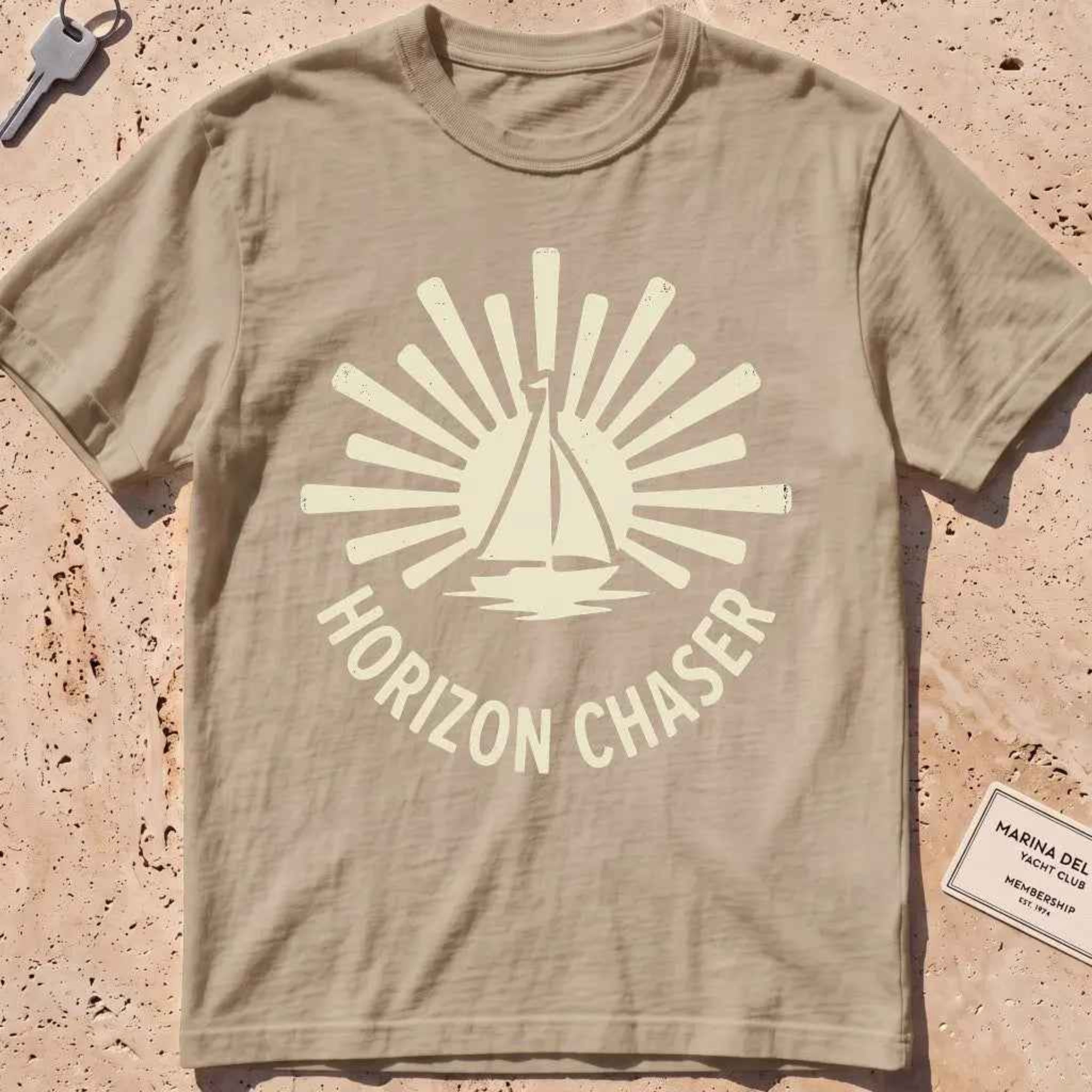 khaki heavyweight tee with a sunburst sailboat "Horizon Chaser" badge.