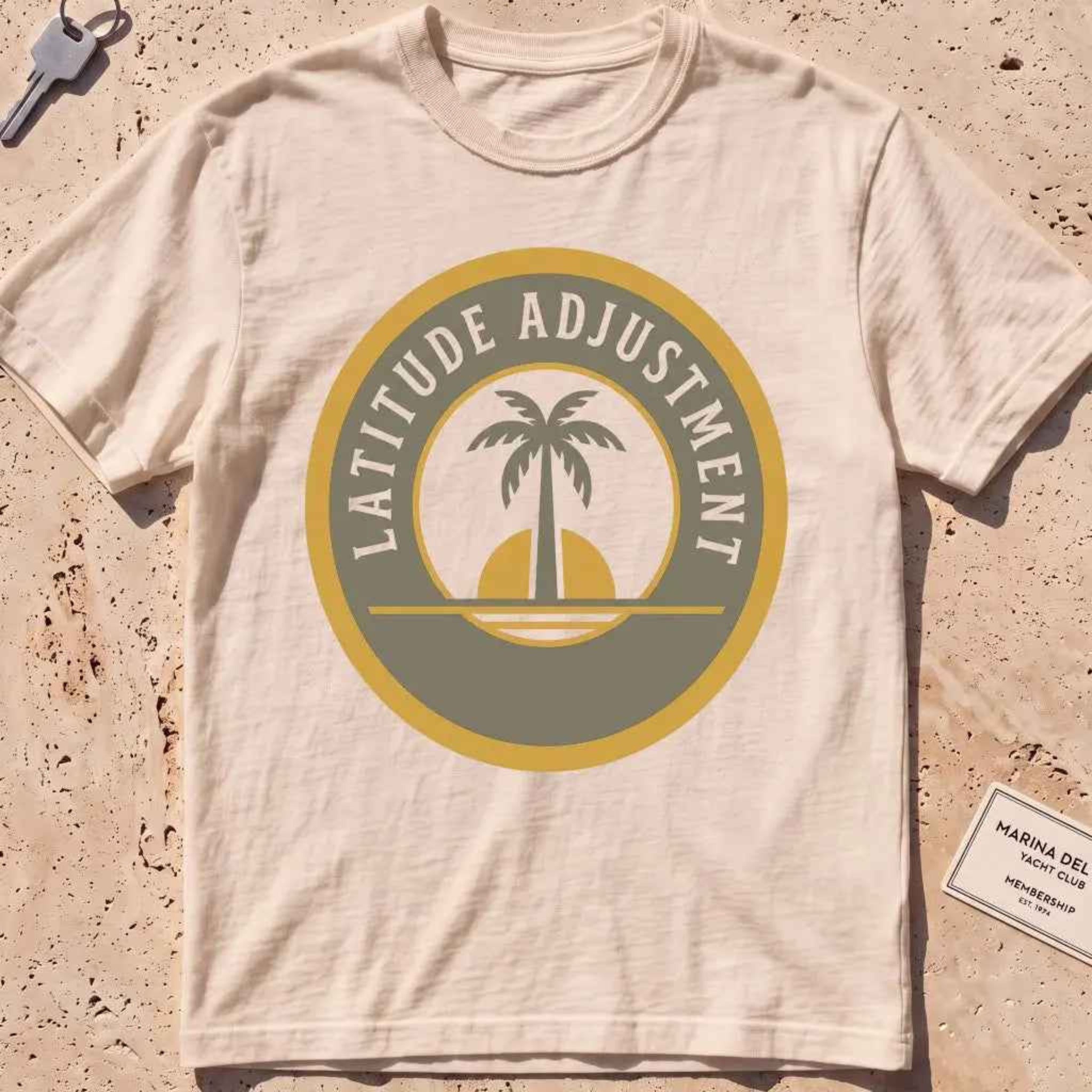 ivory heavyweight tee with a palm-and-sun "Latitude Adjustment" badge.