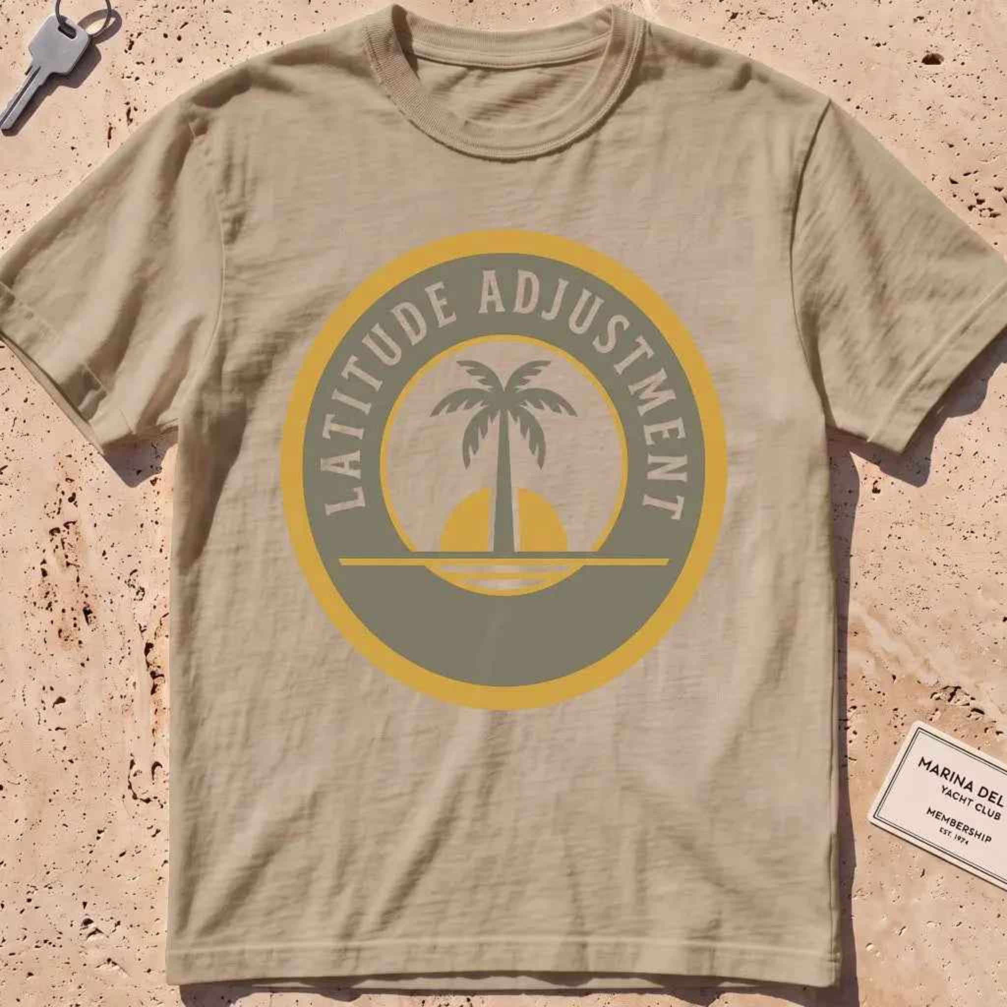 khaki heavyweight tee with a palm-and-sun "Latitude Adjustment" badge.