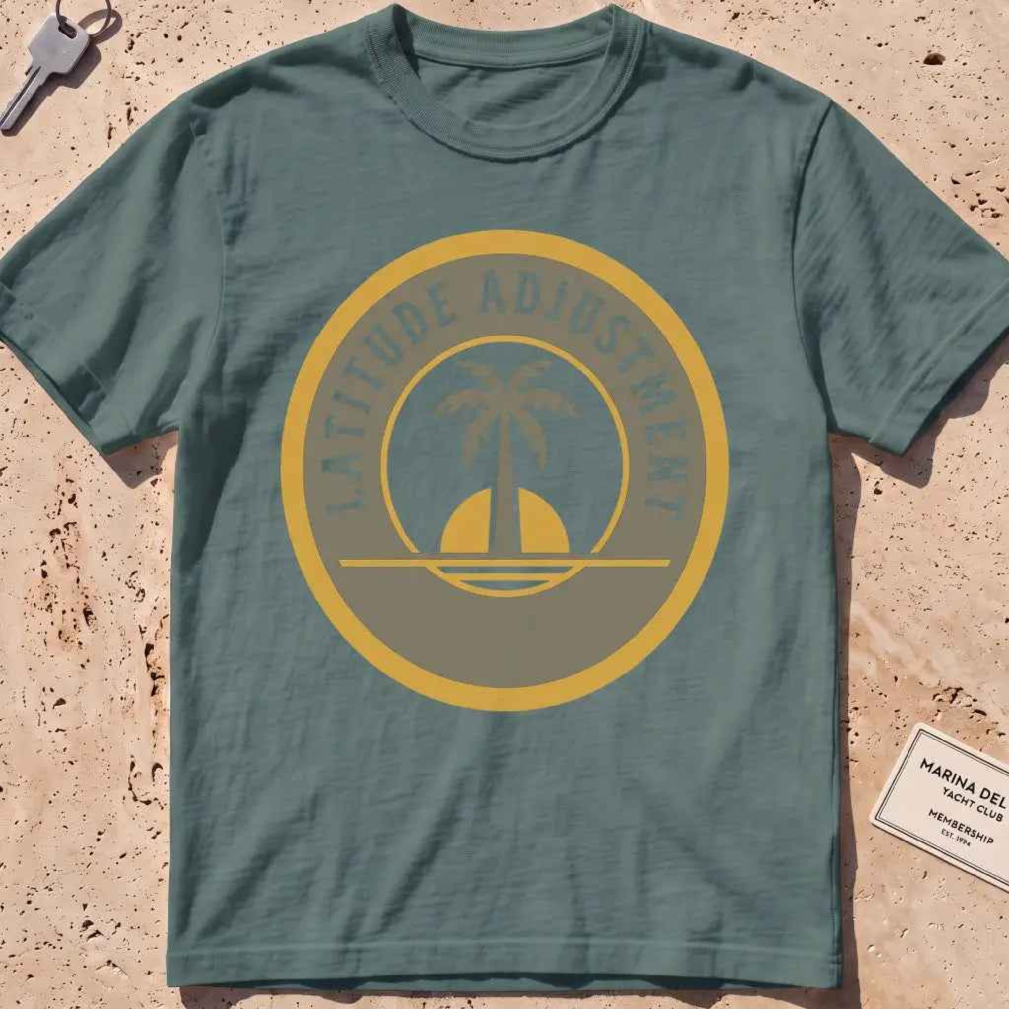 blue spruce heavyweight tee with a palm-and-sun "Latitude Adjustment" badge.