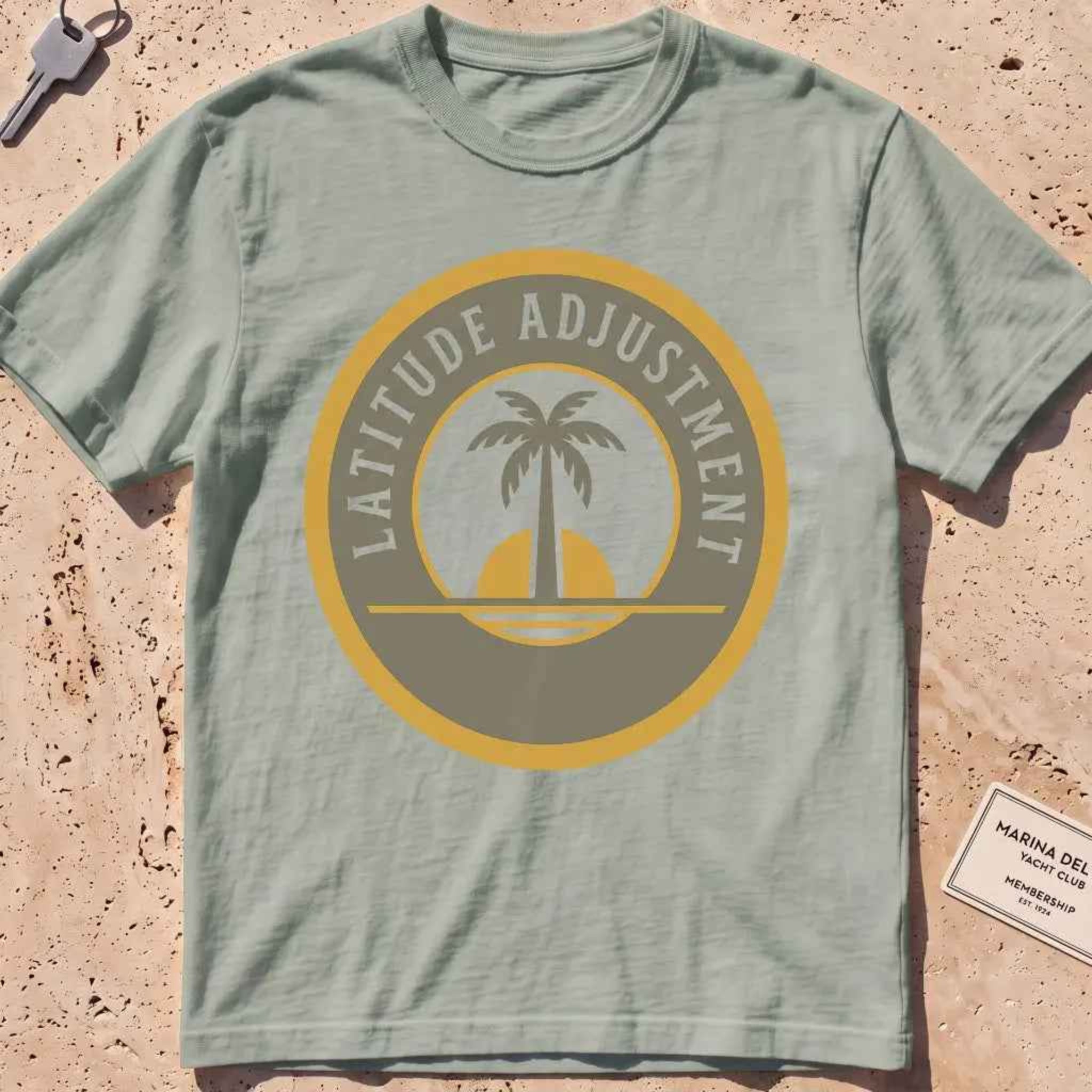 bay heavyweight tee with a palm-and-sun "Latitude Adjustment" badge.