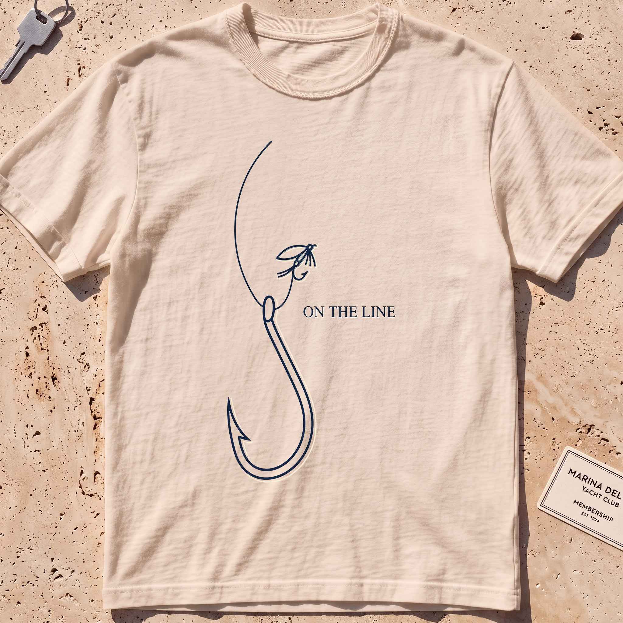 ivory heavyweight tee with a single-line fishing hook and fly graphic.