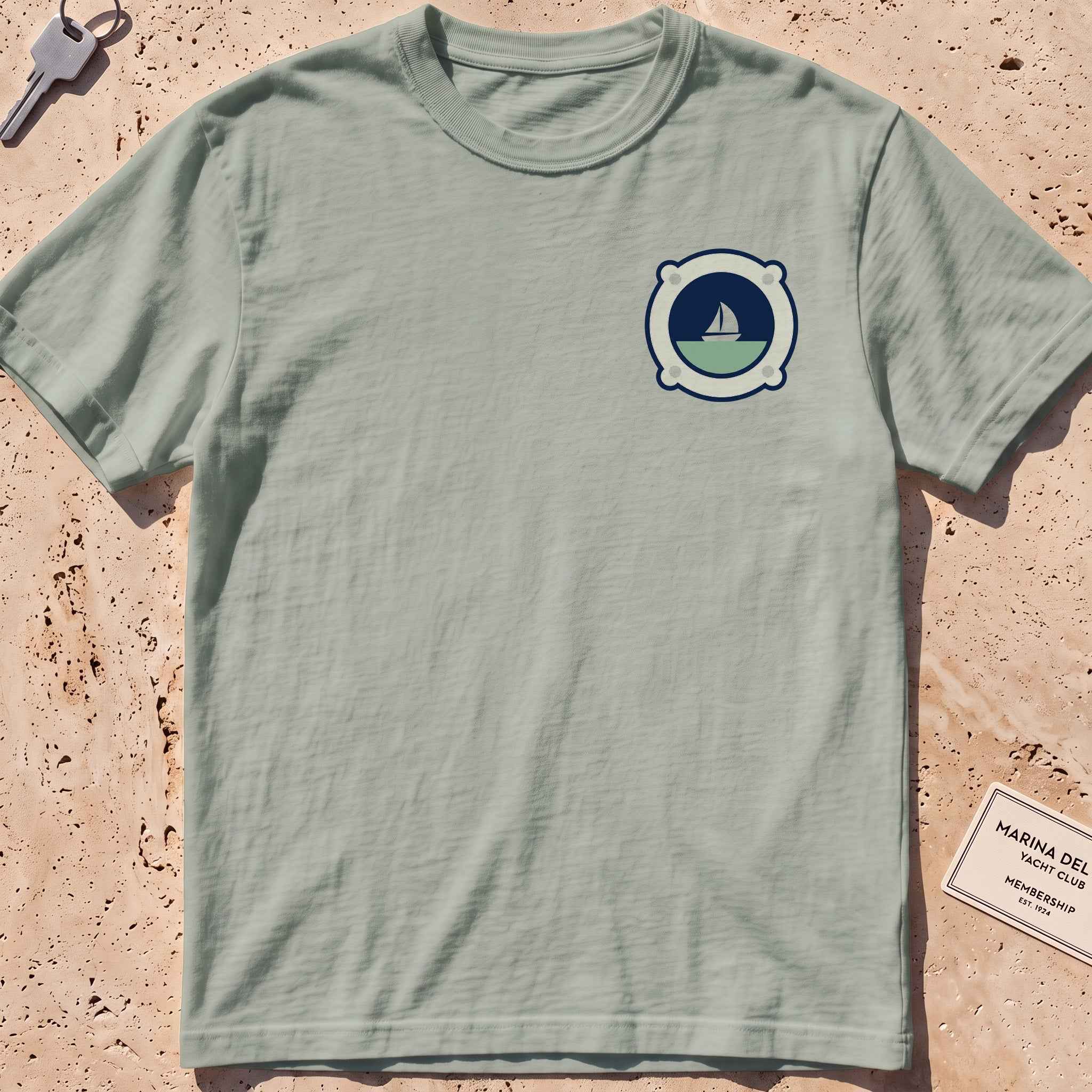 bay heavyweight tee with a porthole framing a sailboat crest graphic.