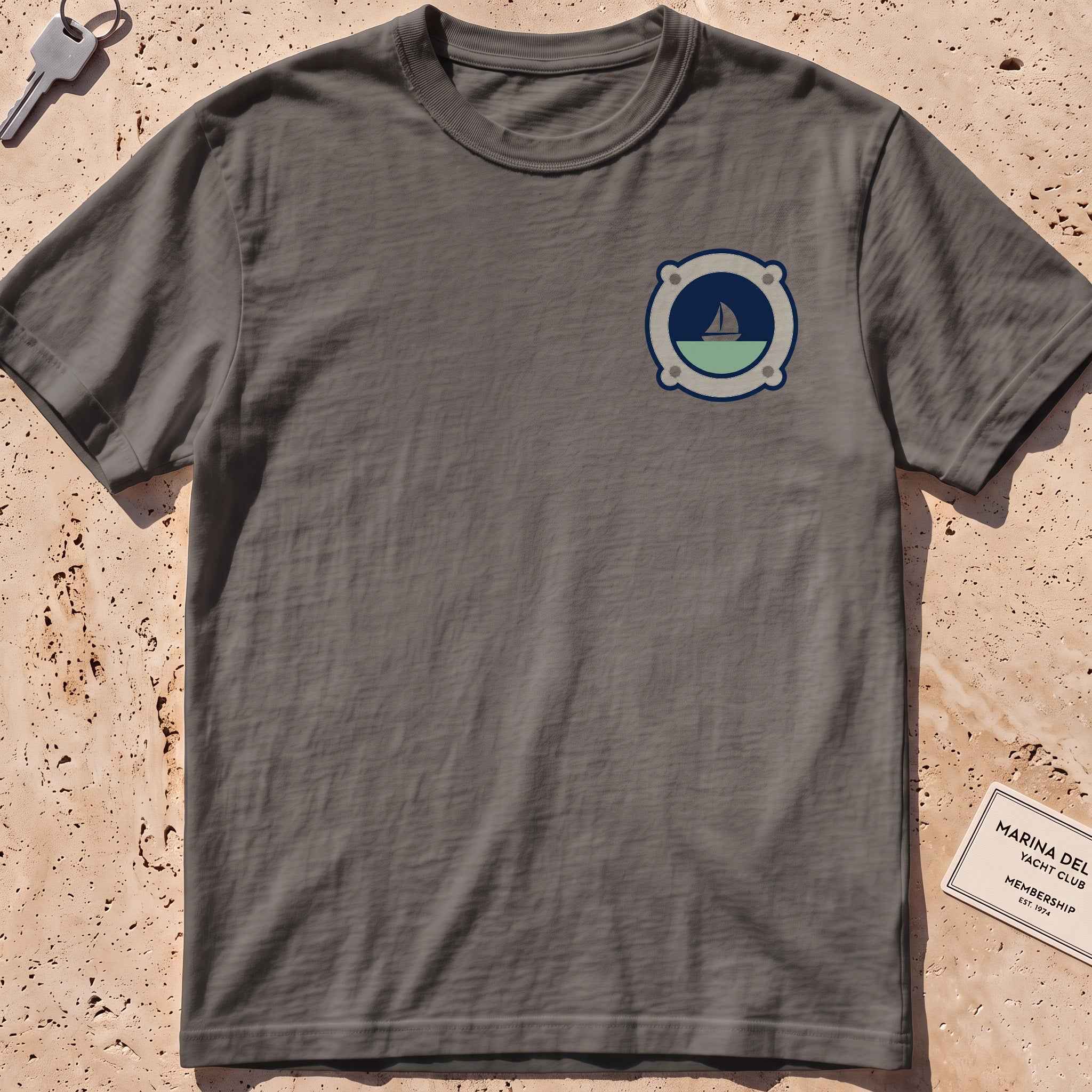 pepper heavyweight tee with a porthole framing a sailboat crest graphic.