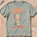 bay heavyweight tee with a playful tiki mug and "Reel Paradise" text graphic.