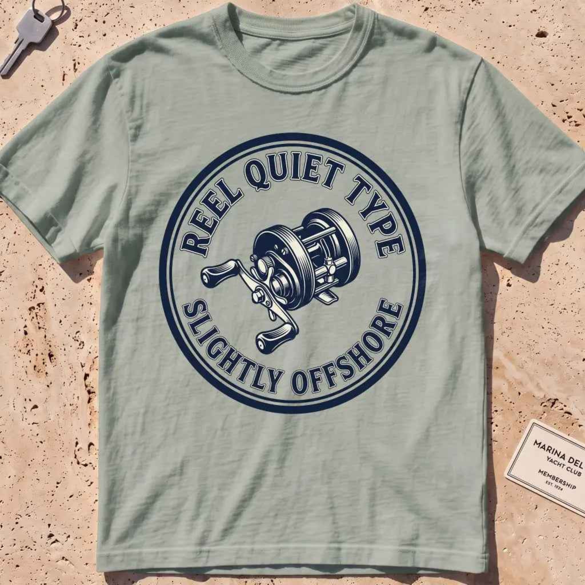 bay heavyweight tee with an engraved fishing-reel "Reel Quiet Type" crest.
