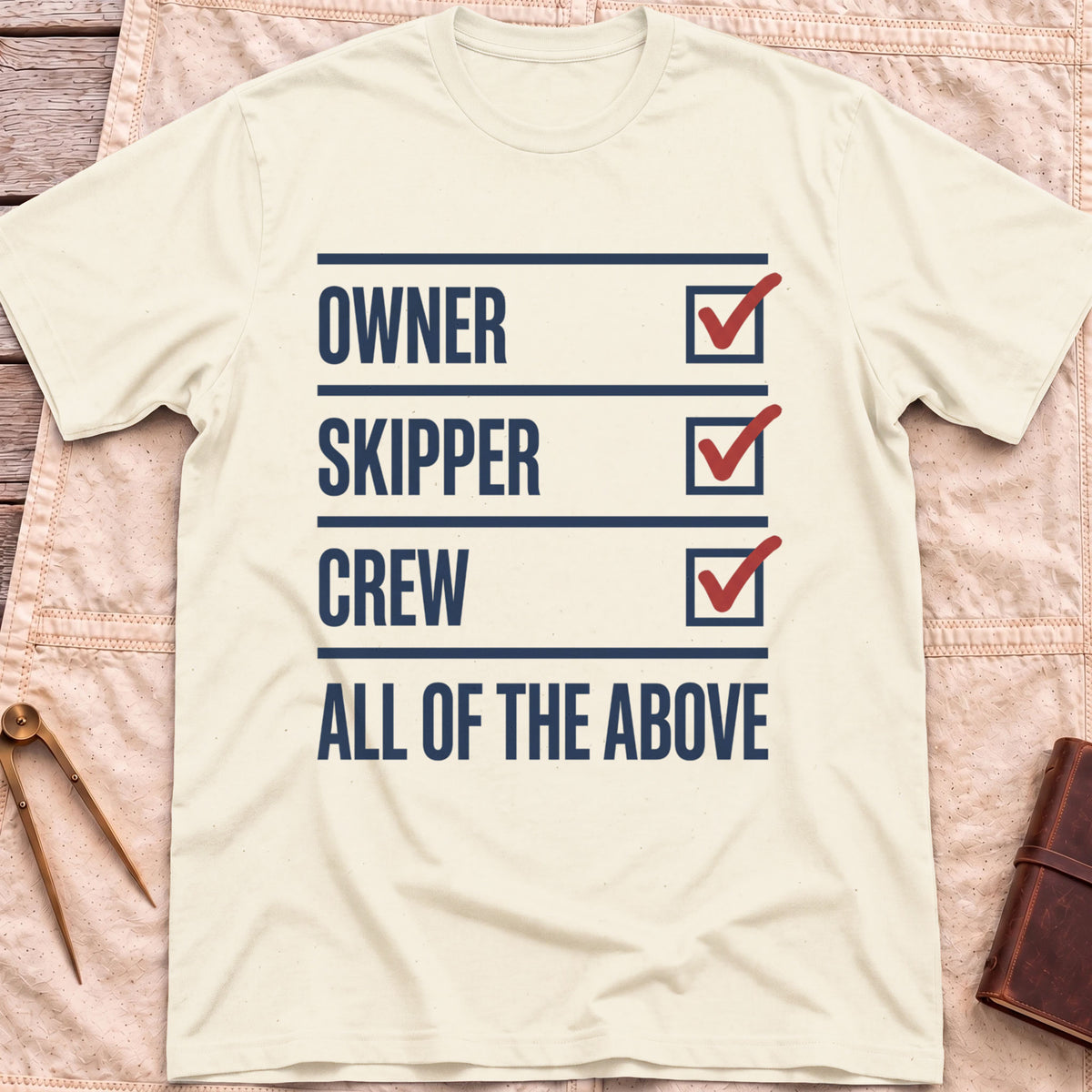 Front view of the natural All of the Above T-Shirt with a checklist of Owner, Skipper and Crew, each ticked in red, above All of the Above.