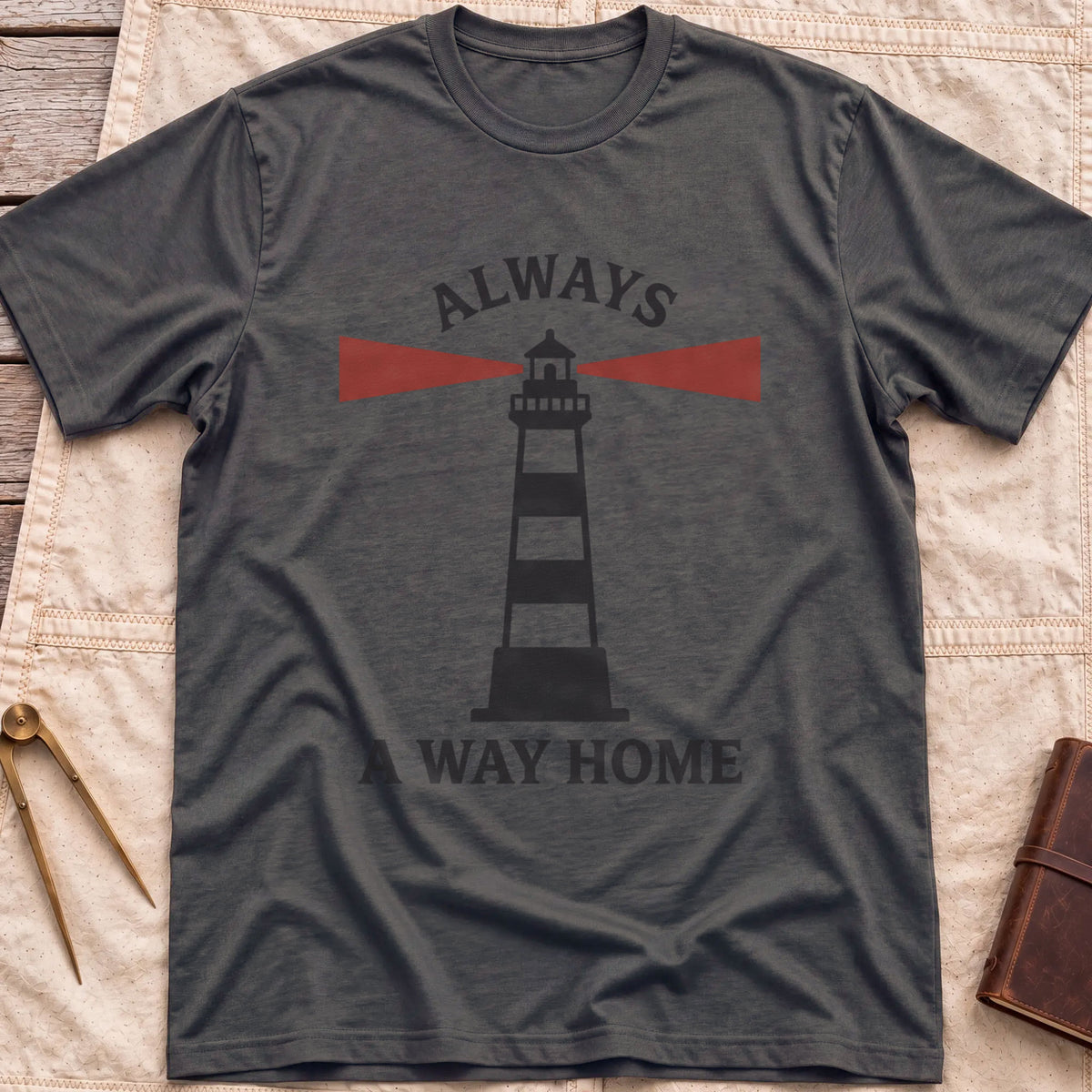 Front view of the dark heather Always a Way Home T-Shirt with a striped lighthouse sending out red beams of light.