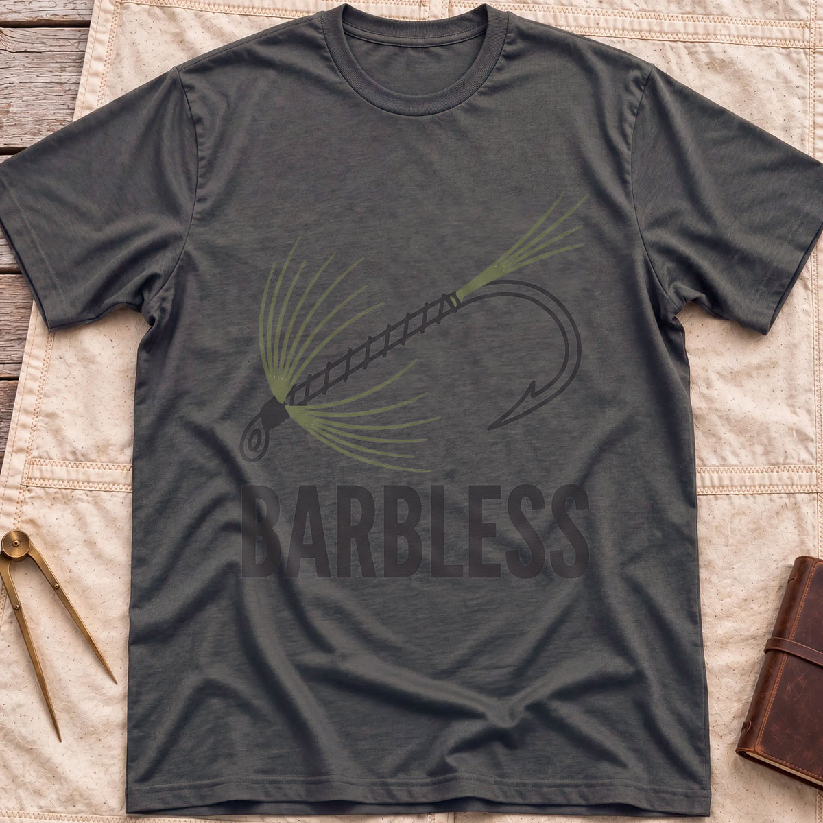 Front view of the dark heather Barbless T-Shirt with a fly-fishing fly on a hook above the word Barbless.