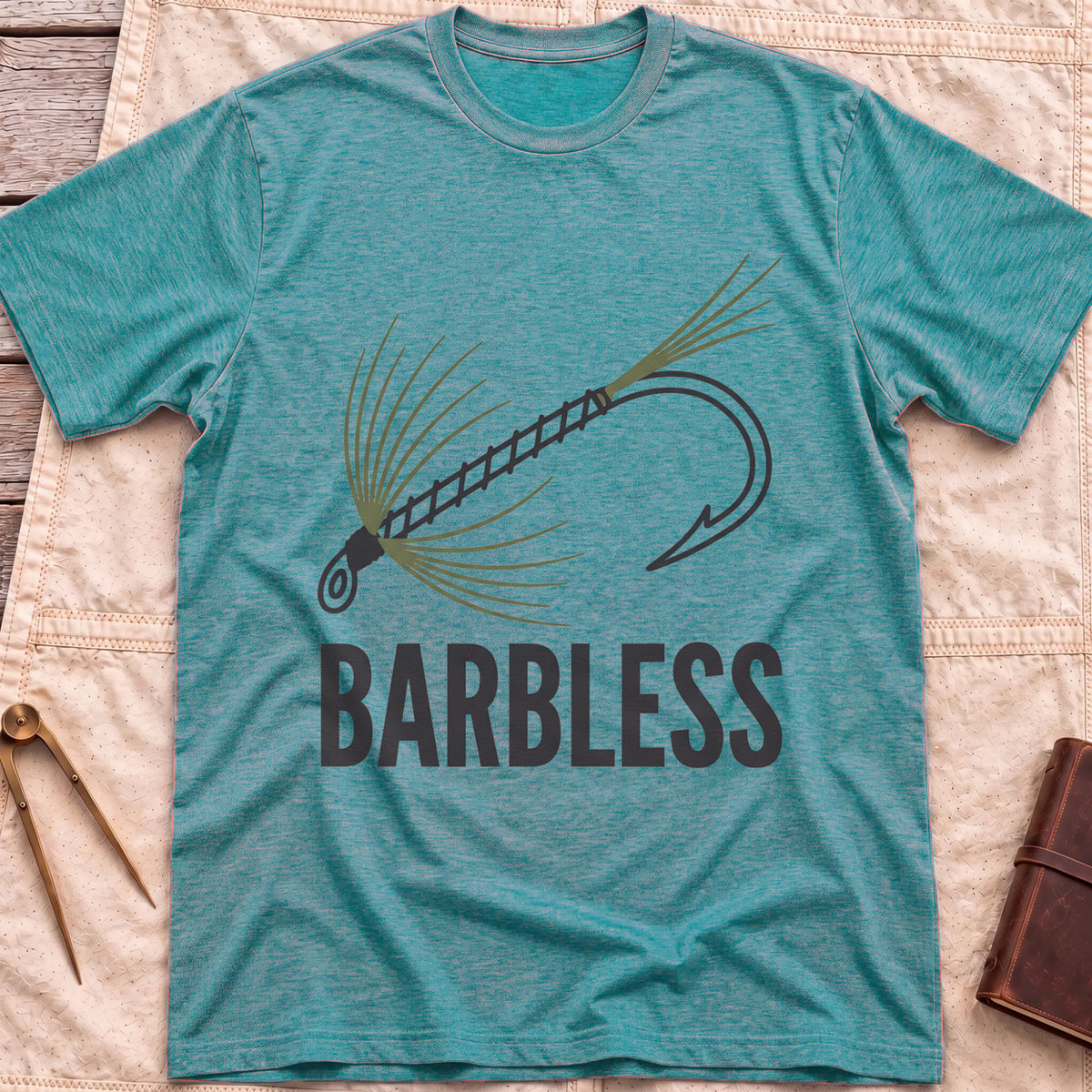 Front view of the heather galapagos blue Barbless T-Shirt with a fly-fishing fly on a hook above the word Barbless.