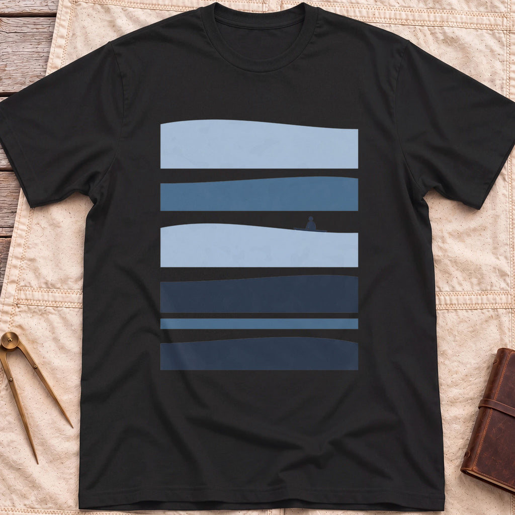 Front view of the black Between Sets T-Shirt with layered bands of blue water and a small figure on a board between them.