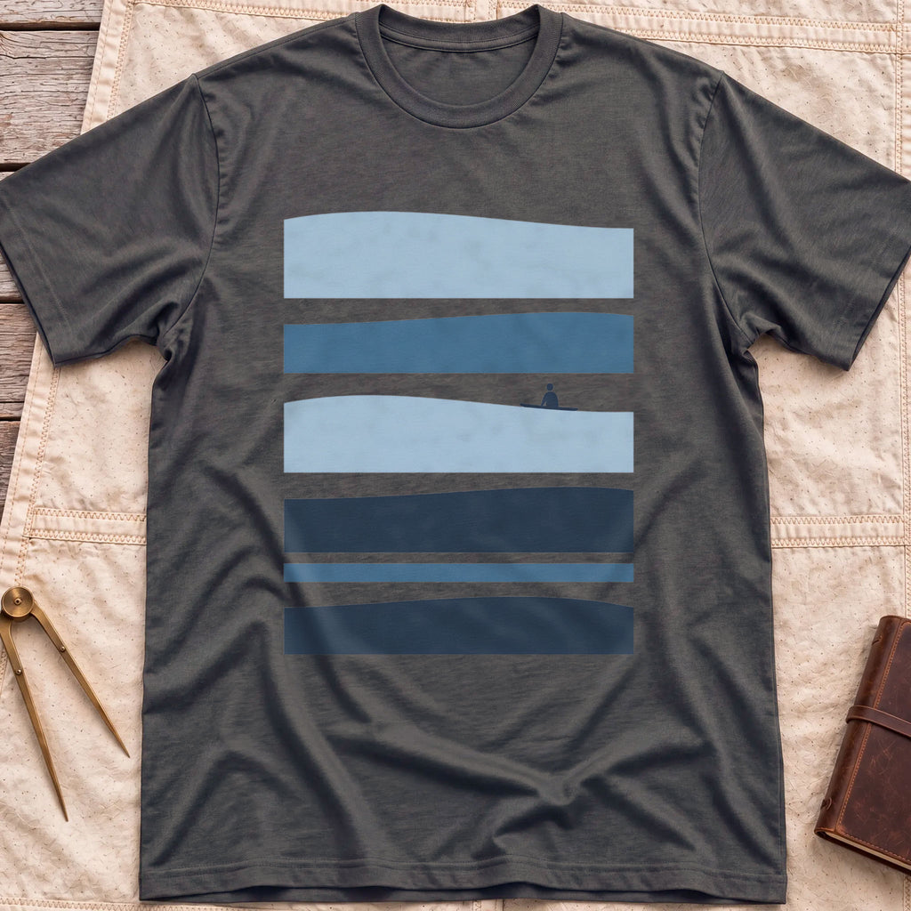 Front view of the dark heather Between Sets T-Shirt with layered bands of blue water and a small figure on a board between them.