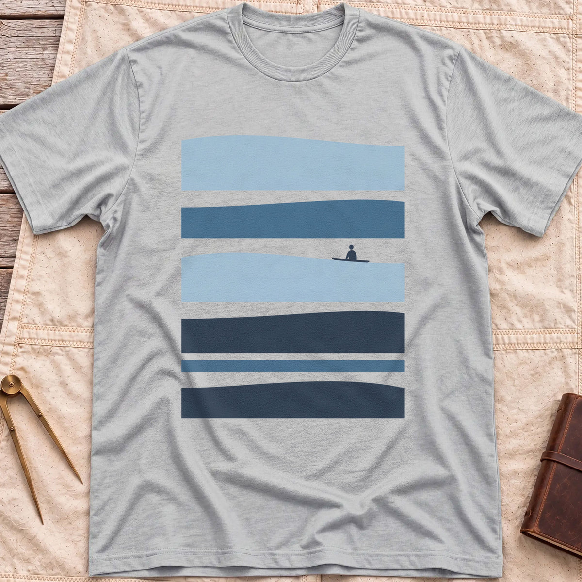 Front view of the sport grey Between Sets T-Shirt with layered bands of blue water and a small figure on a board between them.