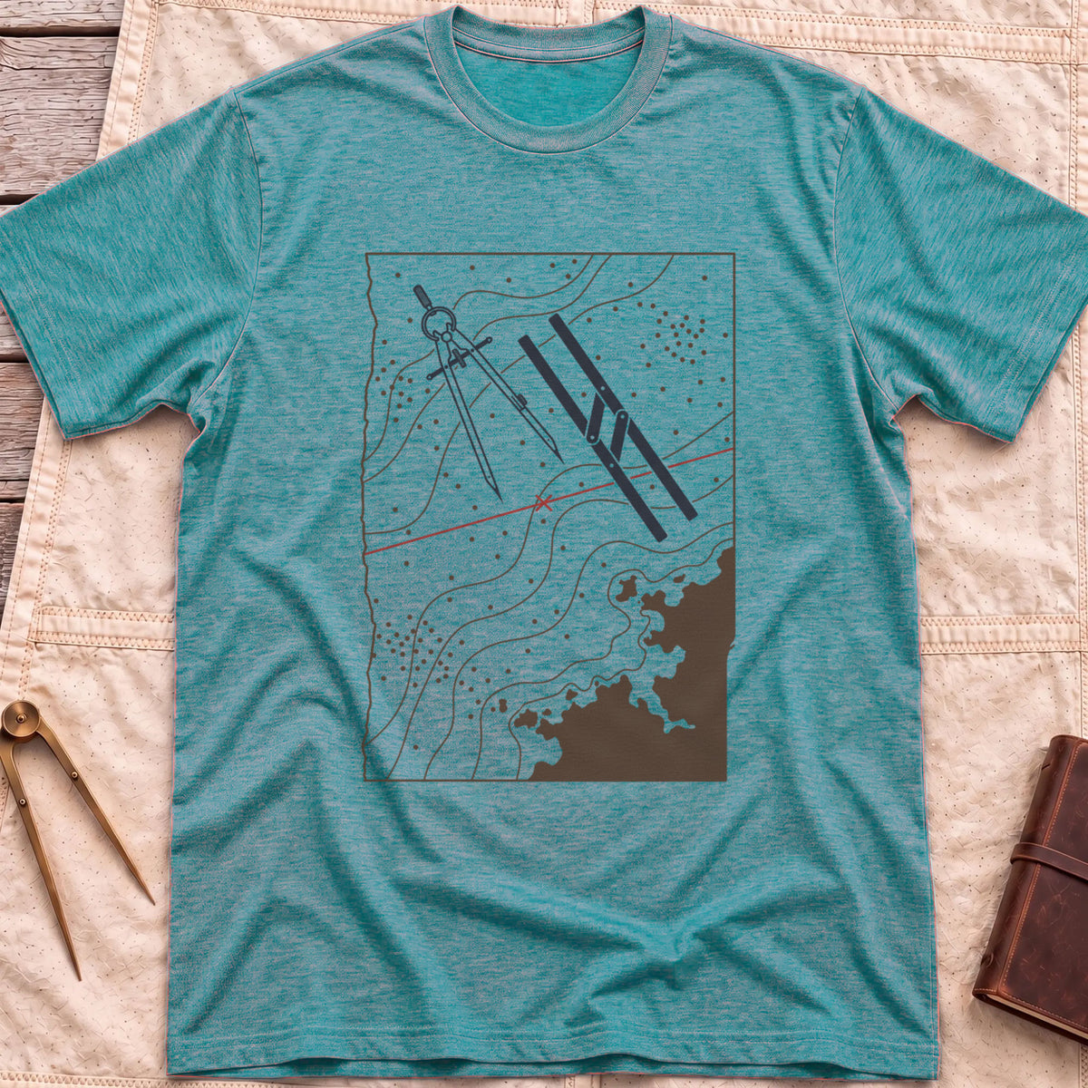 Front view of the heather galapagos blue Chart Table T-Shirt with a chart showing contour lines, dividers, parallel rulers and a red course line.