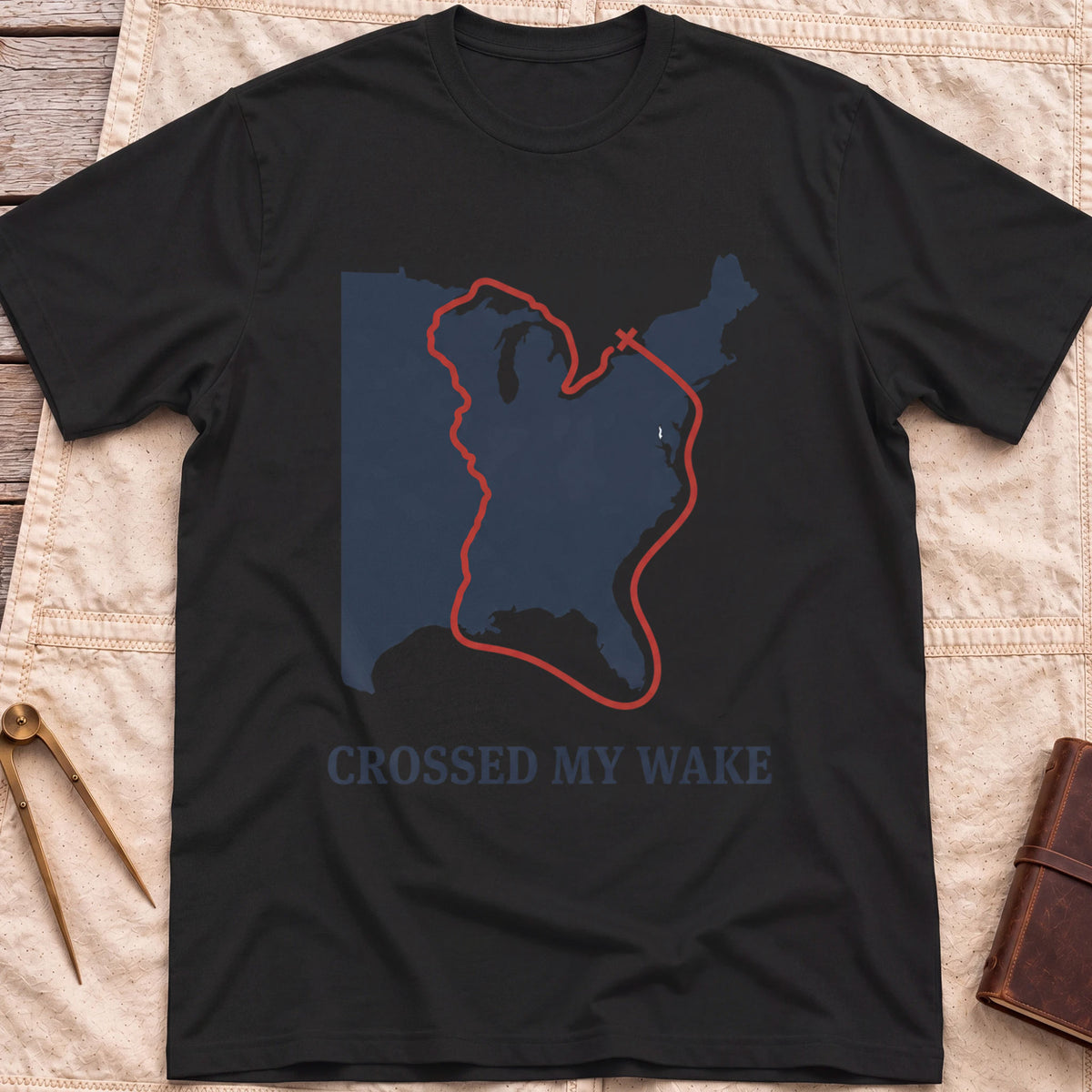 Front view of the black Crossed My Wake T-Shirt with a red route line looping around a map of the eastern United States.
