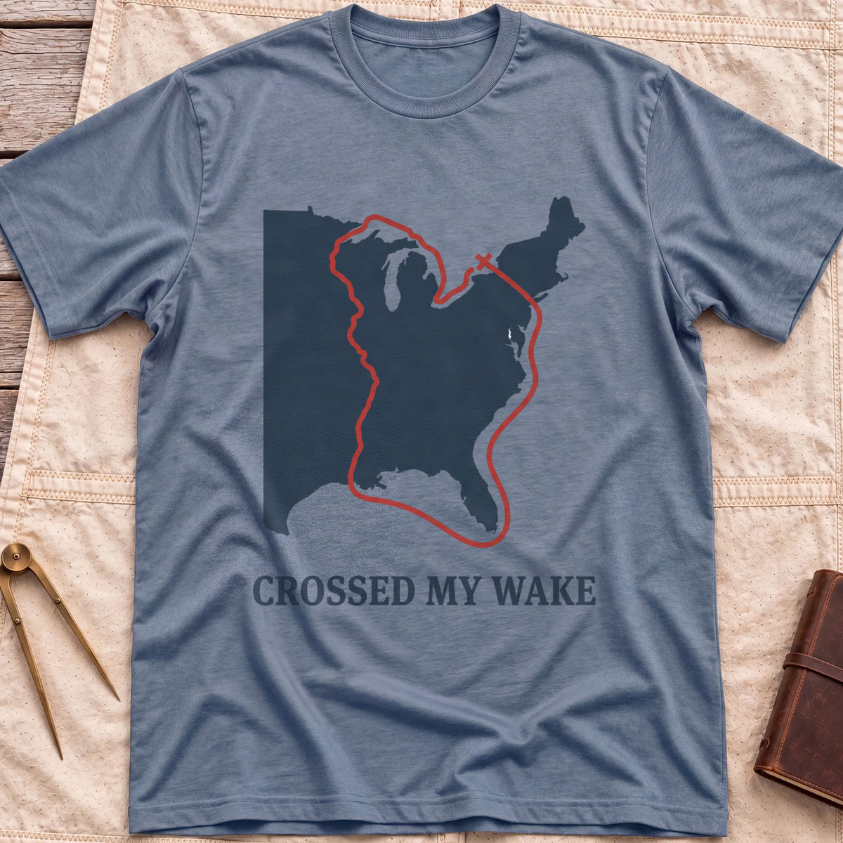 Front view of the heather indigo Crossed My Wake T-Shirt with a red route line looping around a map of the eastern United States.