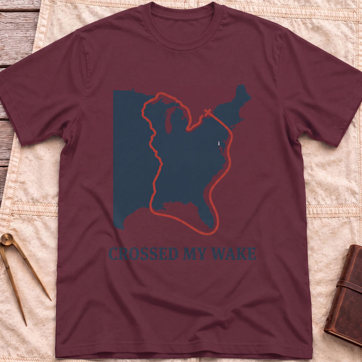 Front view of the maroon Crossed My Wake T-Shirt with a red route line looping around a map of the eastern United States.