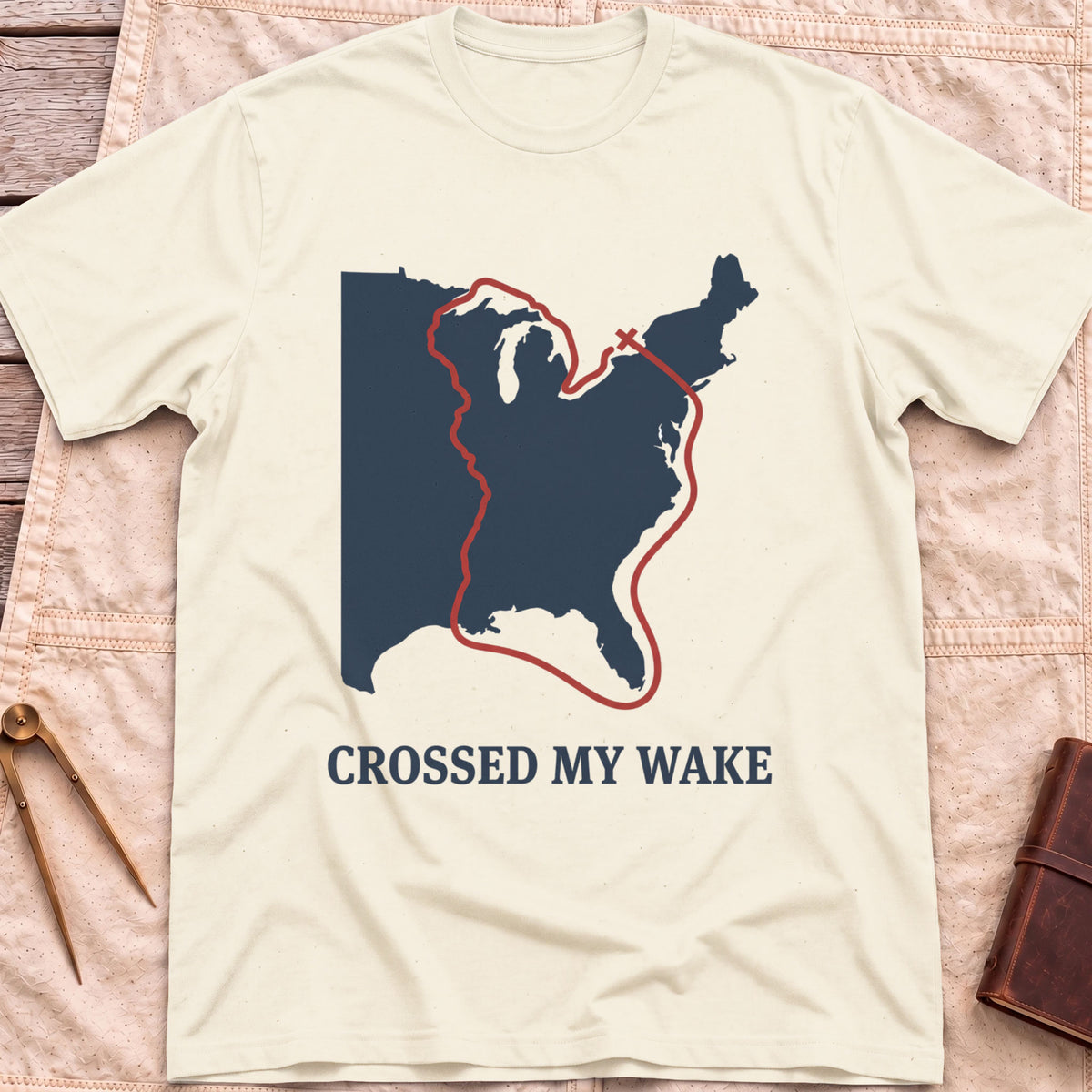 Front view of the natural Crossed My Wake T-Shirt with a red route line looping around a map of the eastern United States.