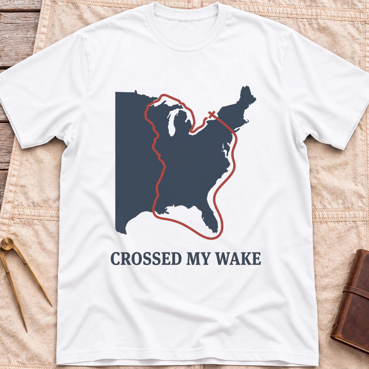 Front view of the white Crossed My Wake T-Shirt with a red route line looping around a map of the eastern United States.