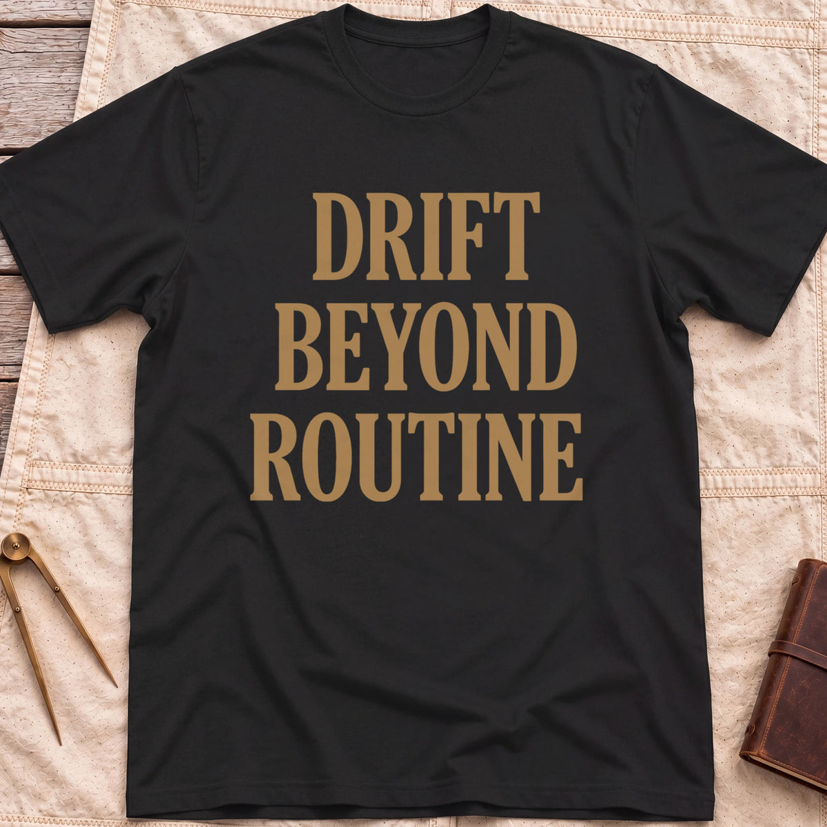 Front view of the black Drift Beyond Routine T-Shirt with the words Drift Beyond Routine in large tan capitals.