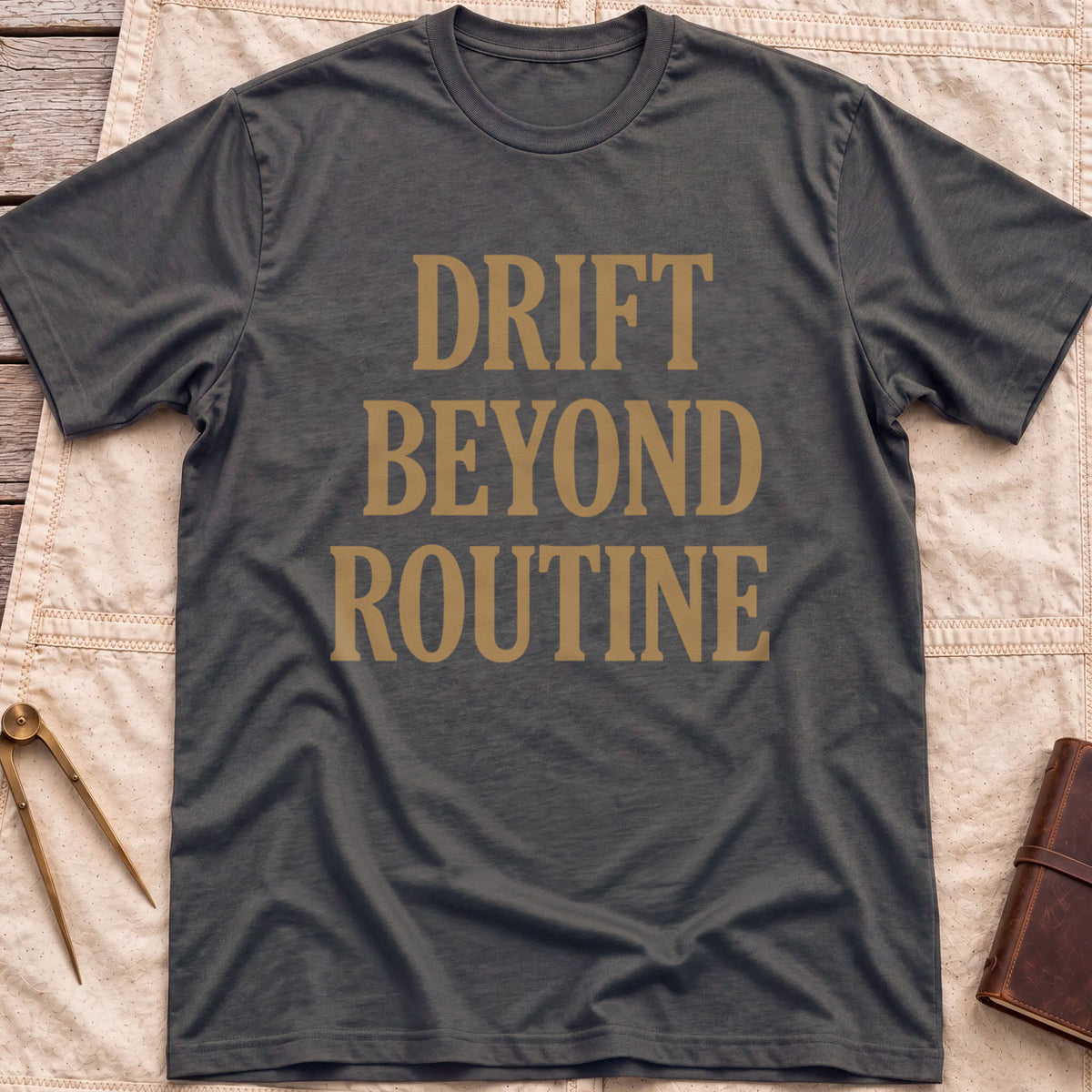 Front view of the dark heather Drift Beyond Routine T-Shirt with the words Drift Beyond Routine in large tan capitals.