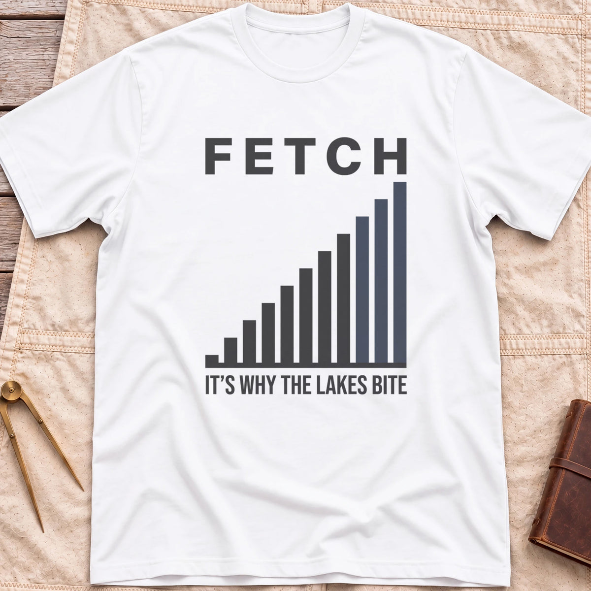 Front view of the white Fetch T-Shirt with a rising bar chart and the words It's Why the Lakes Bite.