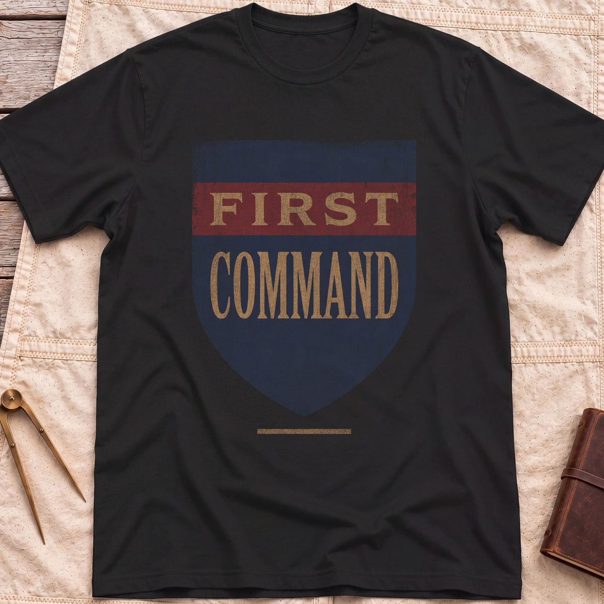 Front view of the black First Command T-Shirt with a distressed navy shield and a red band, lettered First Command.