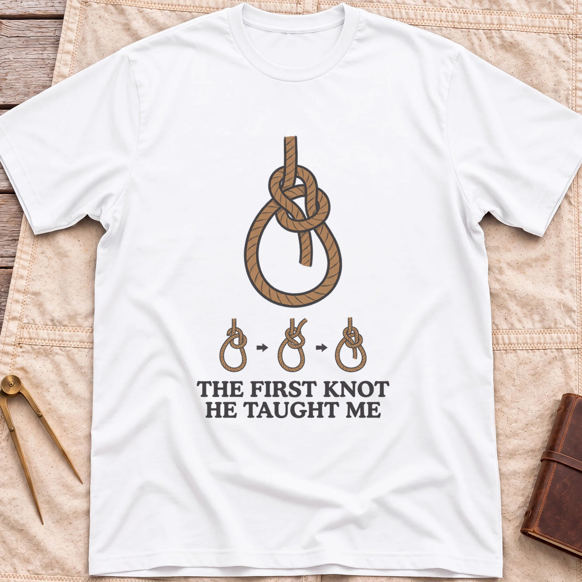 Front view of the white First Knot He Taught Me T-Shirt with a large rope knot above three small diagrams showing it being tied.