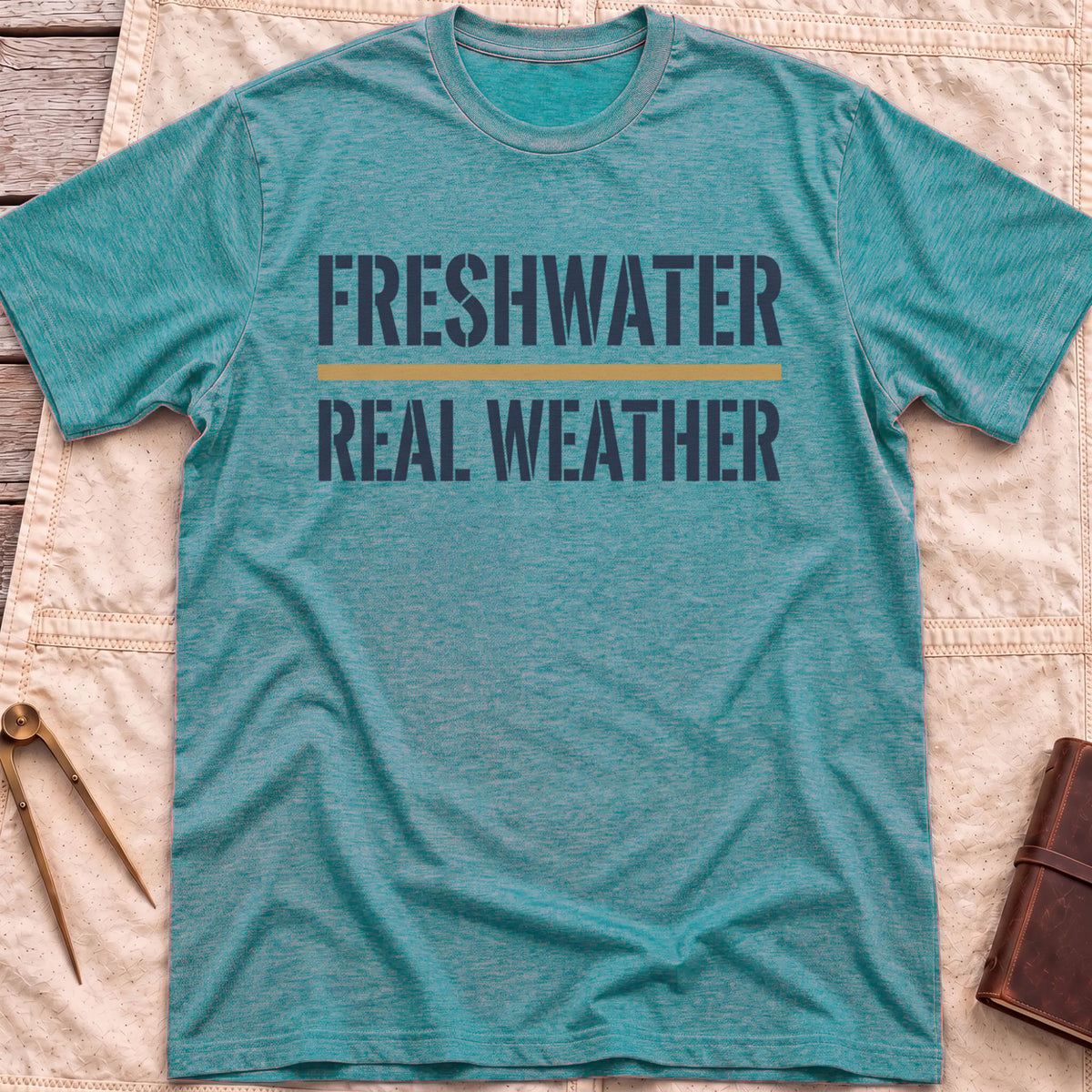 Front view of the heather galapagos blue Freshwater Real Weather T-Shirt with the words Freshwater and Real Weather in bold capitals, split by a tan line.