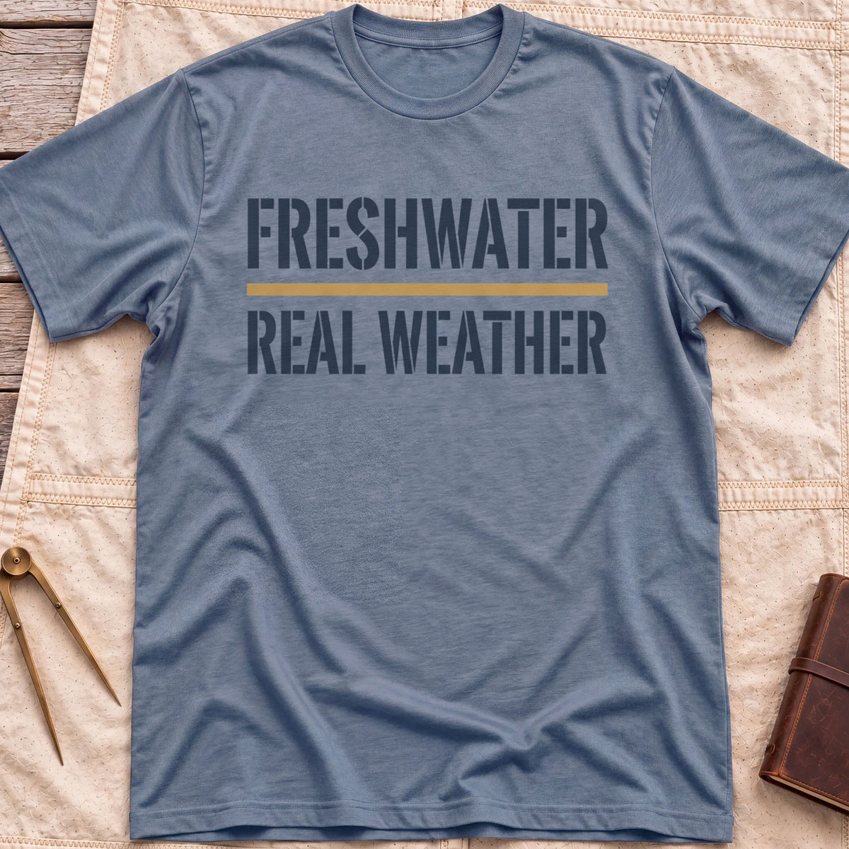 Front view of the heather indigo Freshwater Real Weather T-Shirt with the words Freshwater and Real Weather in bold capitals, split by a tan line.