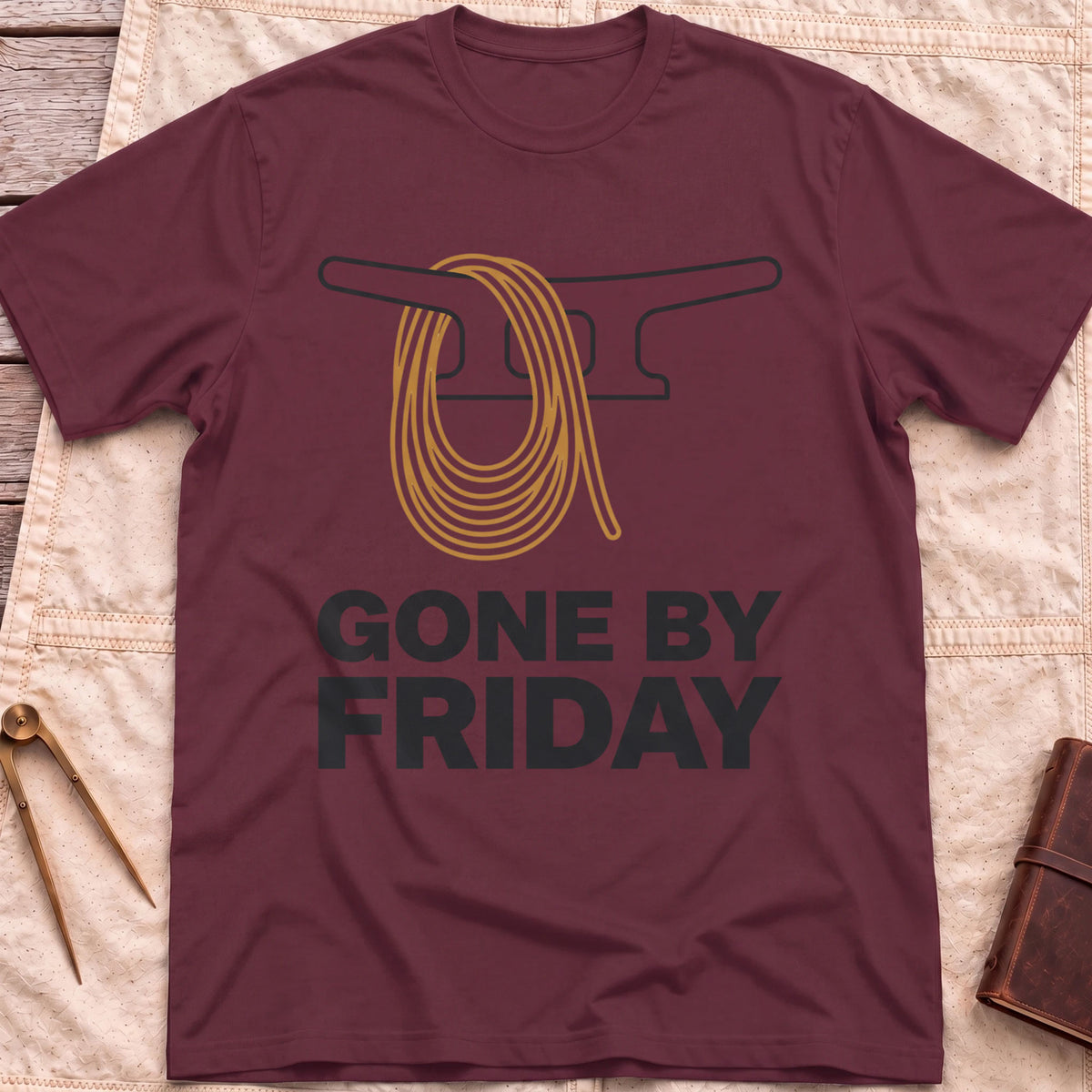 Front view of the maroon Gone by Friday T-Shirt with a coiled rope looped over a dock cleat.