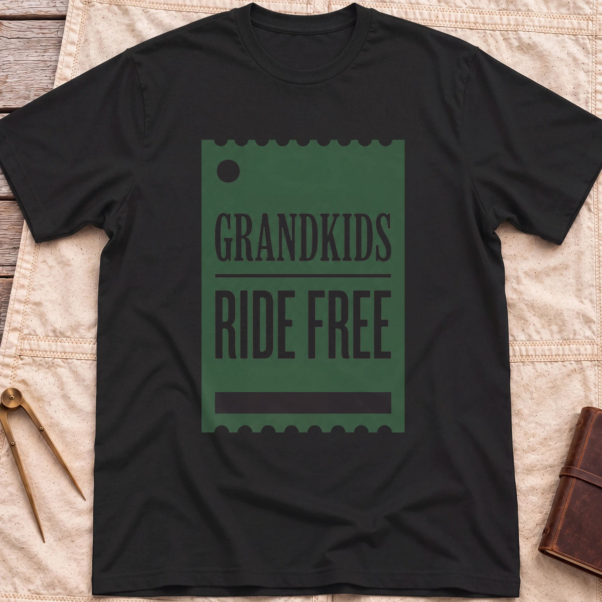 Front view of the black Grandkids Ride Free T-Shirt with a green ticket-shaped graphic reading Grandkids Ride Free.