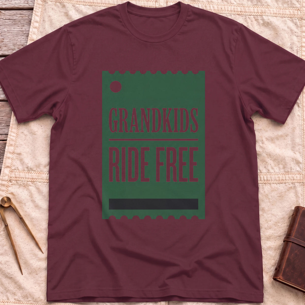 Front view of the maroon Grandkids Ride Free T-Shirt with a green ticket-shaped graphic reading Grandkids Ride Free.