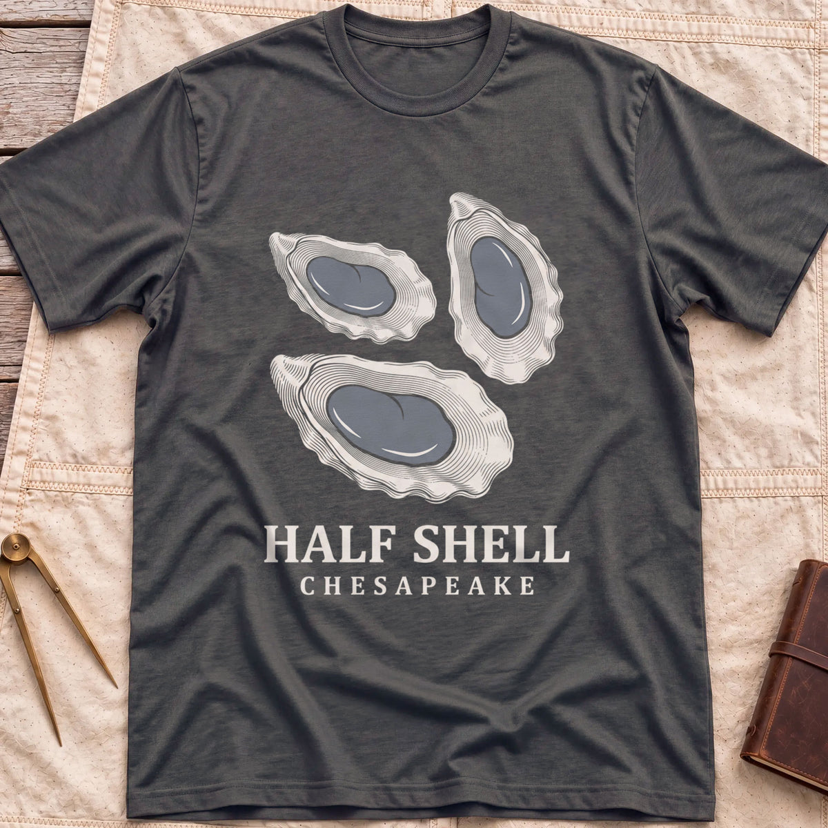 Front view of the dark heather Half Shell T-Shirt with three detailed oyster shells above the words Half Shell, Chesapeake.