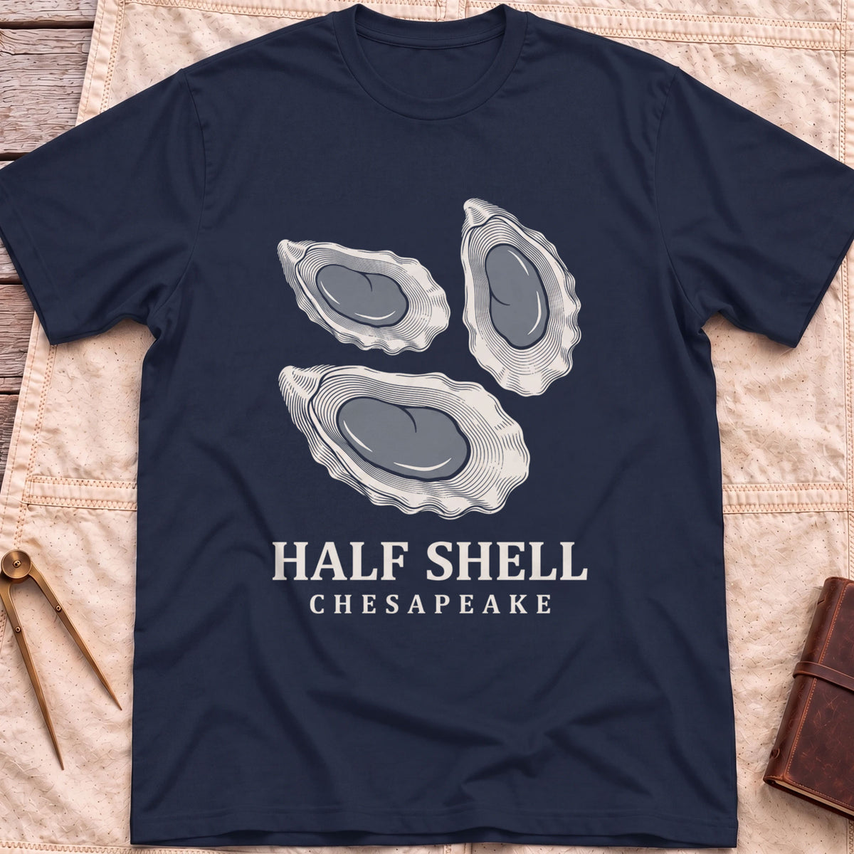 Front view of the navy Half Shell T-Shirt with three detailed oyster shells above the words Half Shell, Chesapeake.