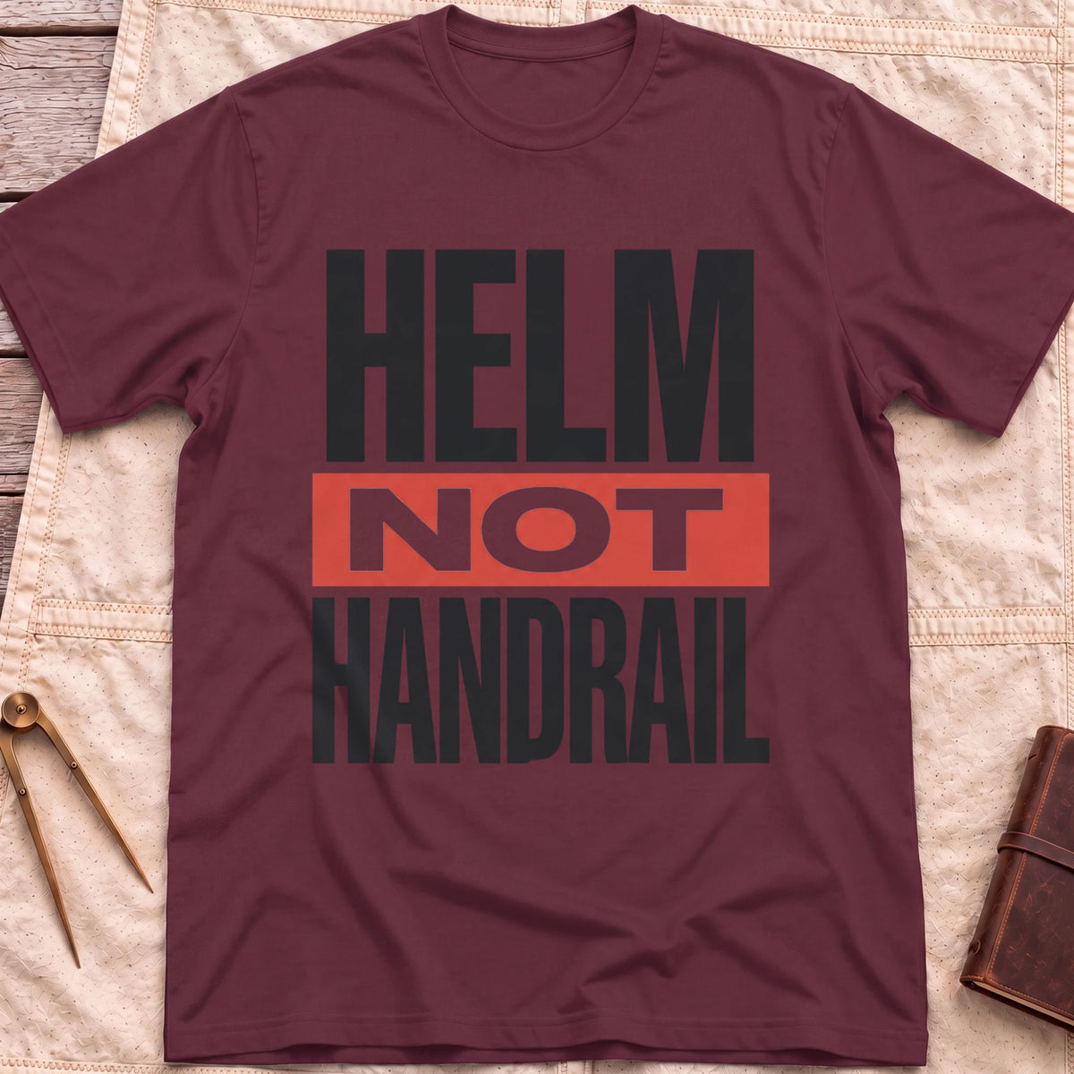 Front view of the maroon Helm Not Handrail T-Shirt with the words Helm Not Handrail in heavy capitals, Not set on a red bar.