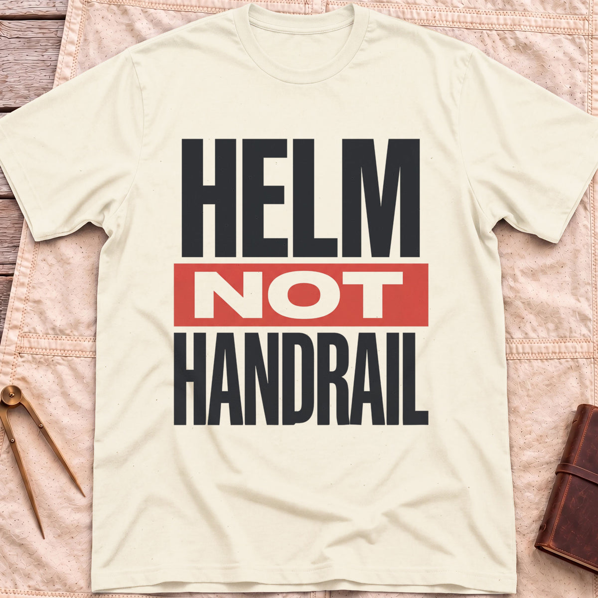 Front view of the natural Helm Not Handrail T-Shirt with the words Helm Not Handrail in heavy capitals, Not set on a red bar.