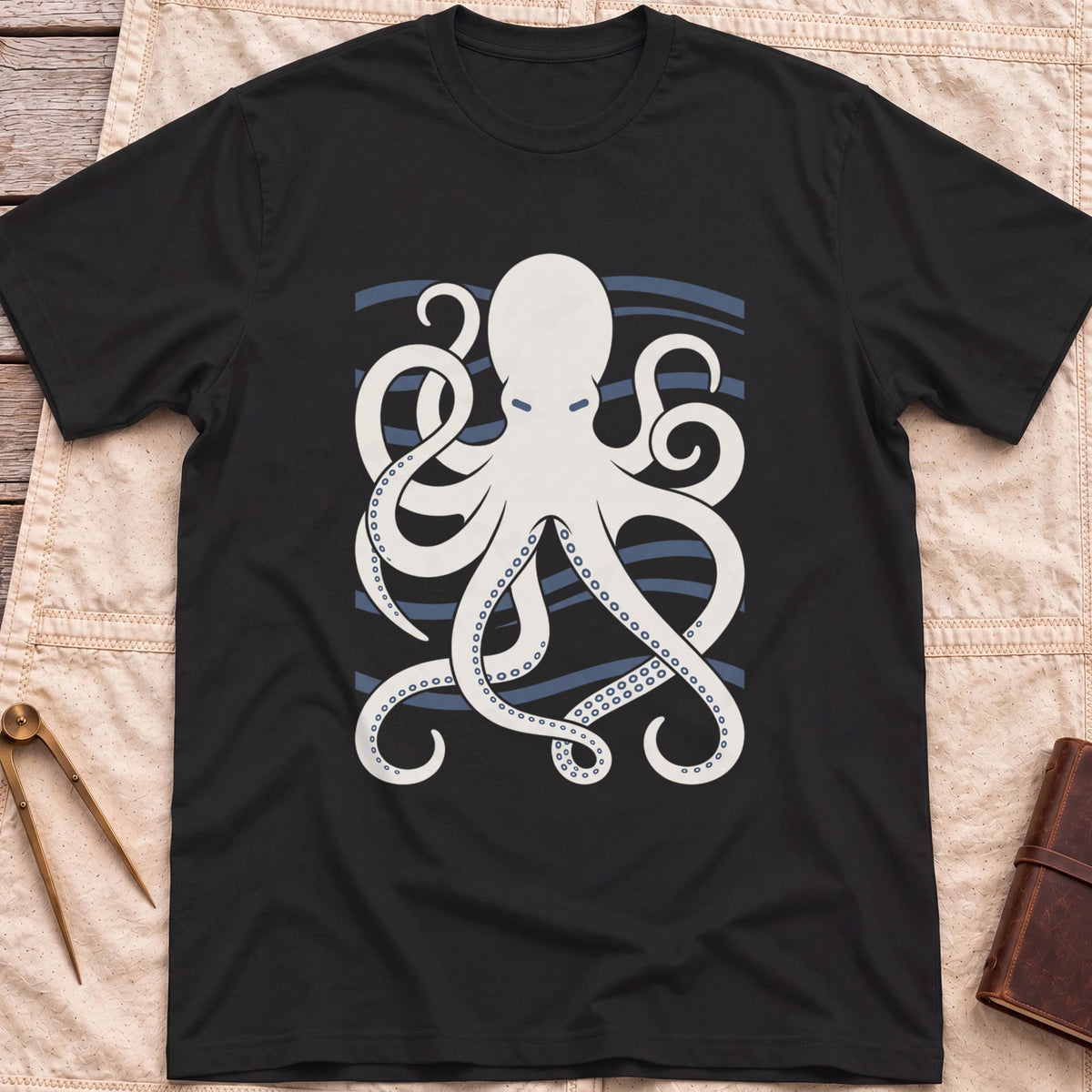 Front view of the black Holdfast T-Shirt with a cream octopus spreading curling tentacles over blue wave lines.