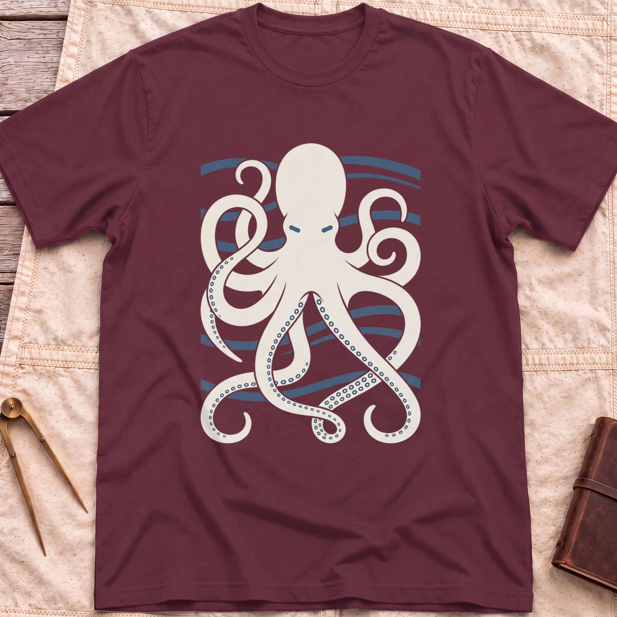 Front view of the maroon Holdfast T-Shirt with a cream octopus spreading curling tentacles over blue wave lines.